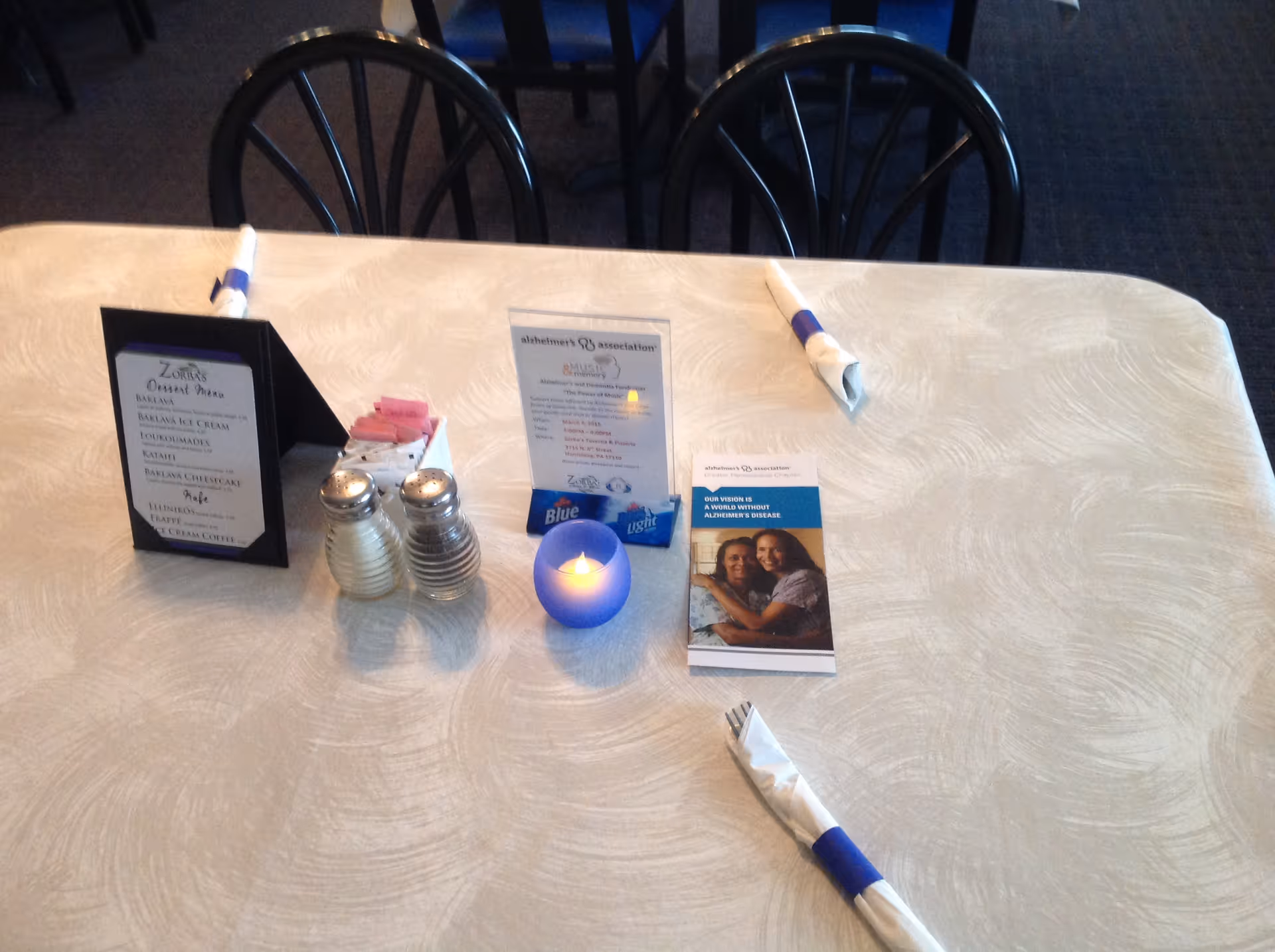 A table set for dining with menus, a candle, and napkins in a senior care facility.