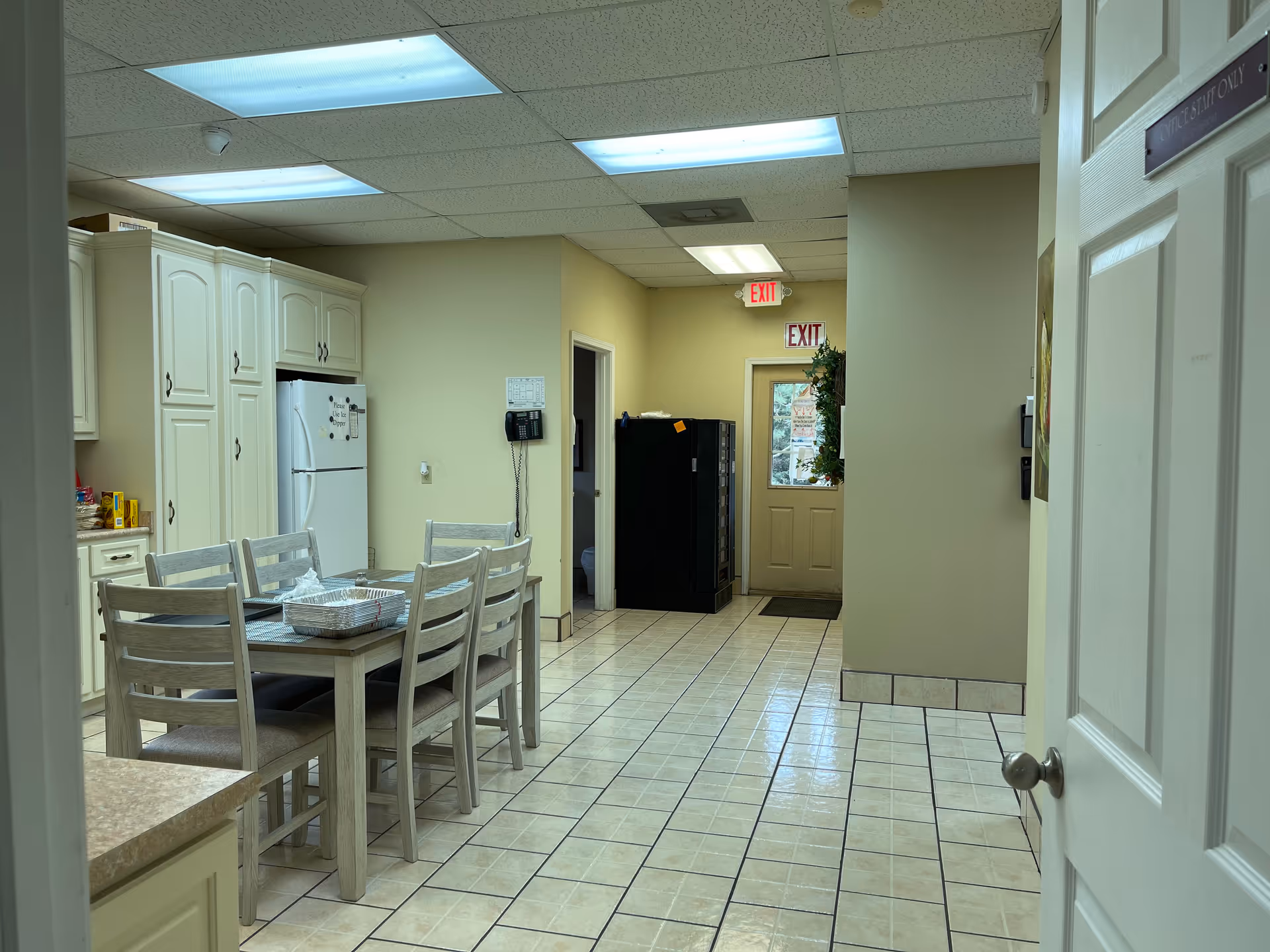 Communal dining area with a wooden table, chairs, and kitchen cabinets.