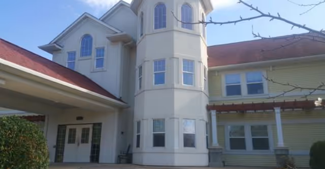 Cream-colored senior living facility exterior with a central tower and red roof.