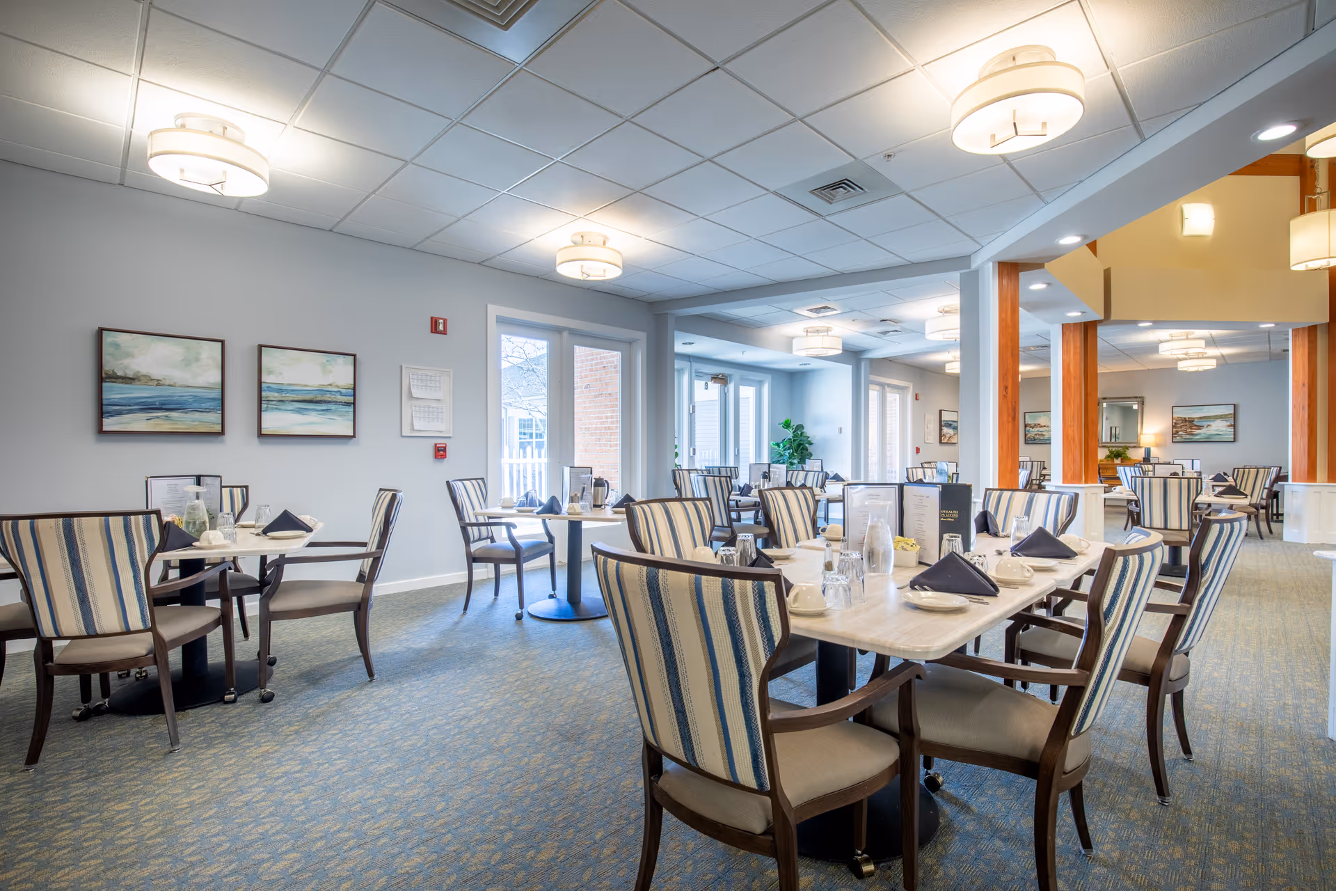 Well-lit dining room with striped chairs and tables set for meals.