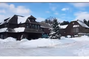 Snow-covered Noble Horizons senior living facility with dark wood exterior and surrounding trees