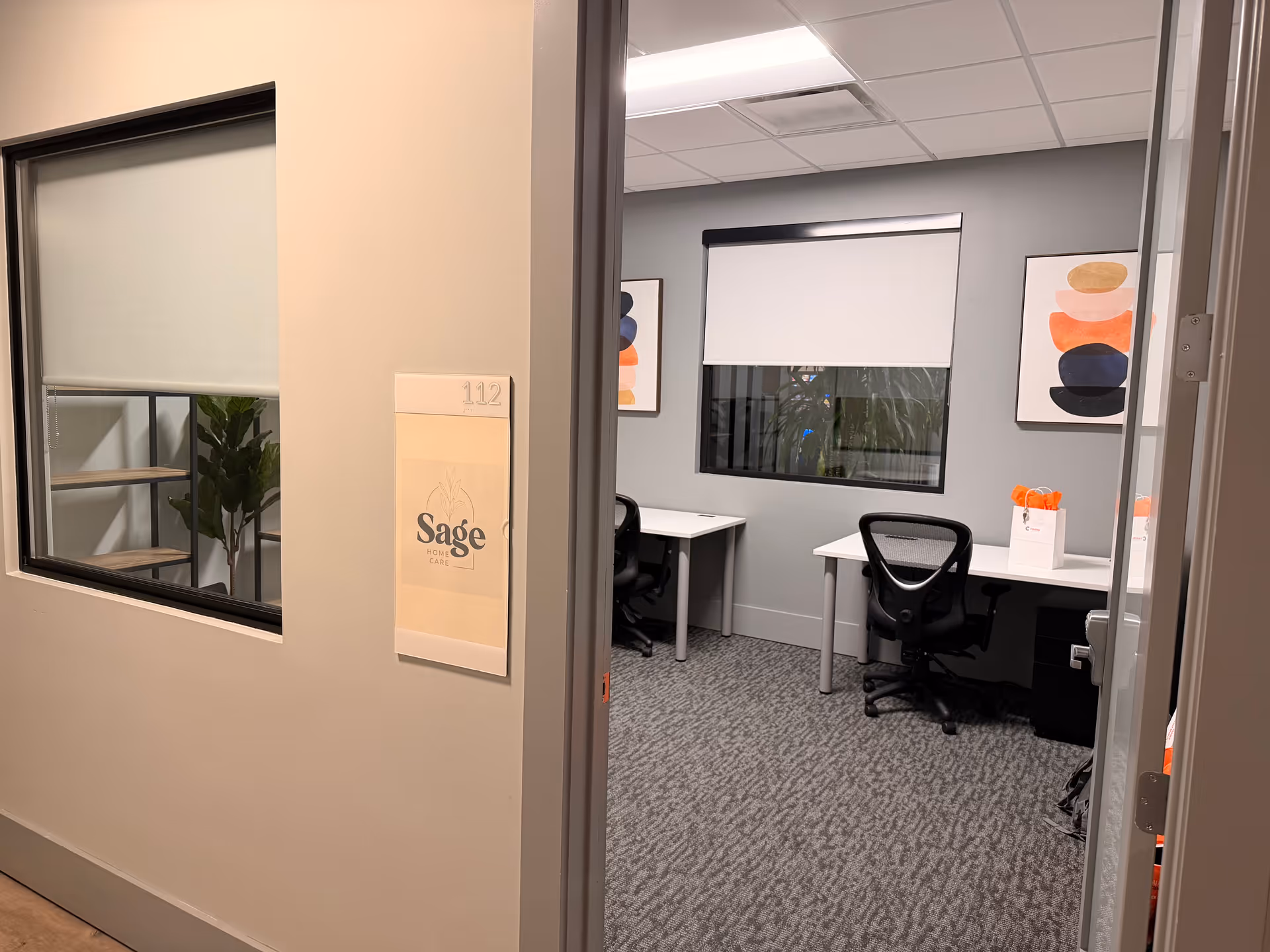 Interior office area with two desks, chairs, and wall art in Sage Home Care.
