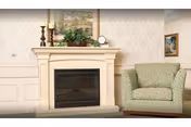 A cozy living room features a lit fireplace, patterned wallpaper, and two green armchairs.