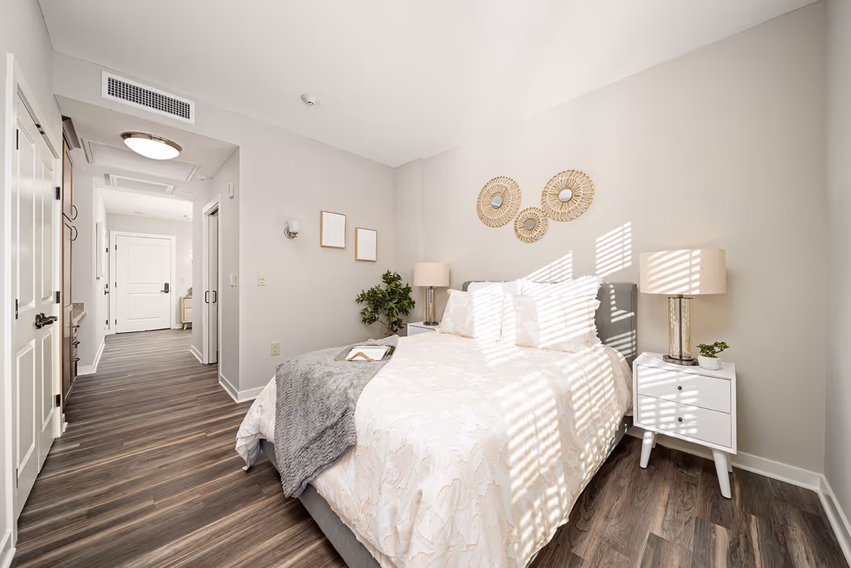 Bright bedroom with a large bed, nightstands, lamps, and decorative wall art.