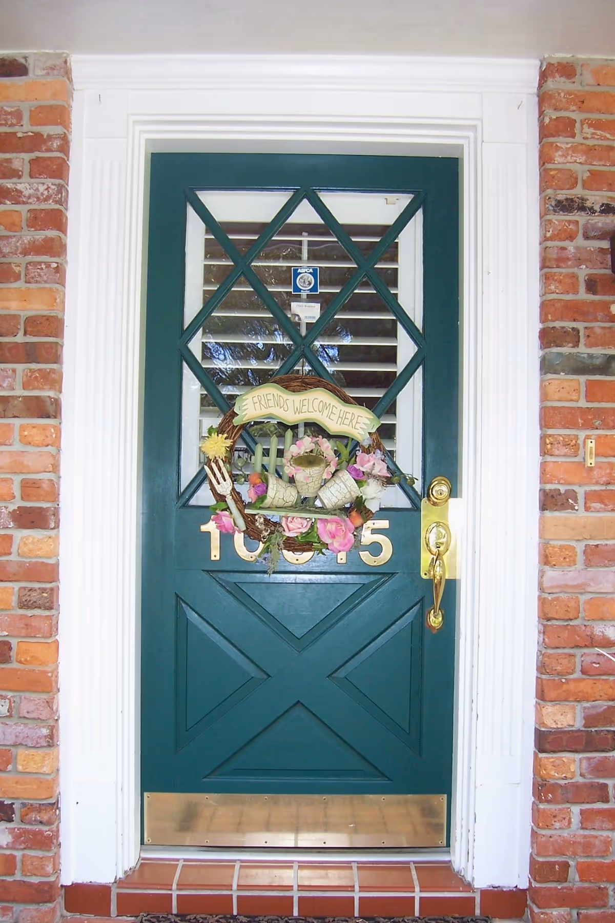 Green front door with a wreath, brick exterior, and the house number 105.