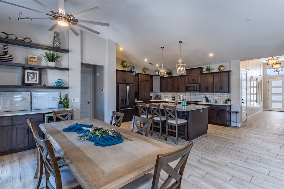 Open-concept kitchen and dining area with dark wood cabinets, island, and pendant lights.