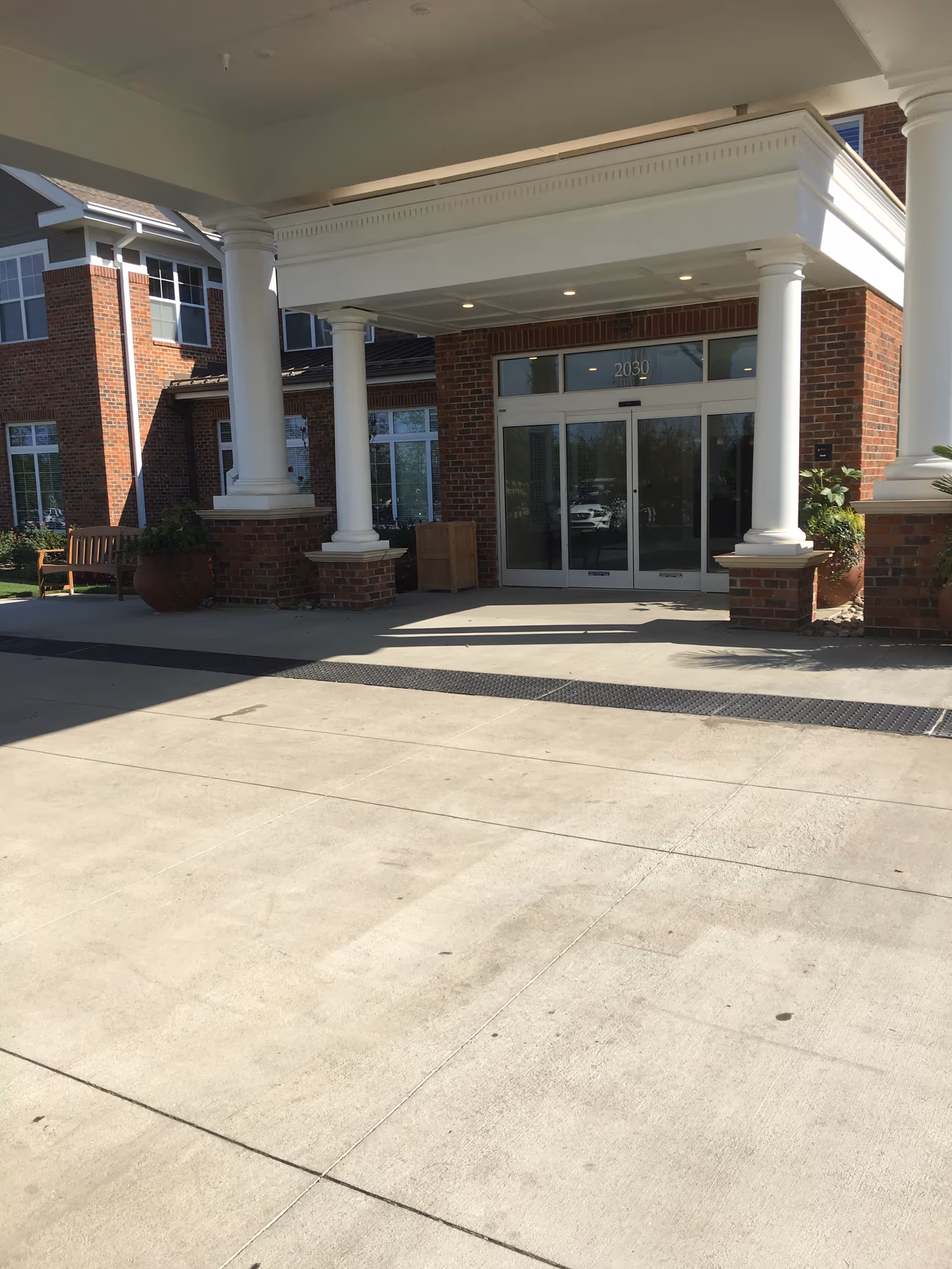 Exterior view of Windsor Run entrance with white columns and glass doors.