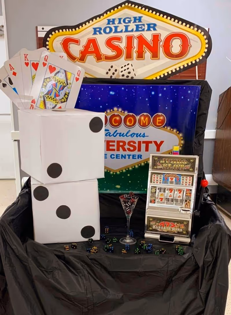 Indoor Evercare at University casino-themed display with large dice, playing cards, and a slot-machine prop.