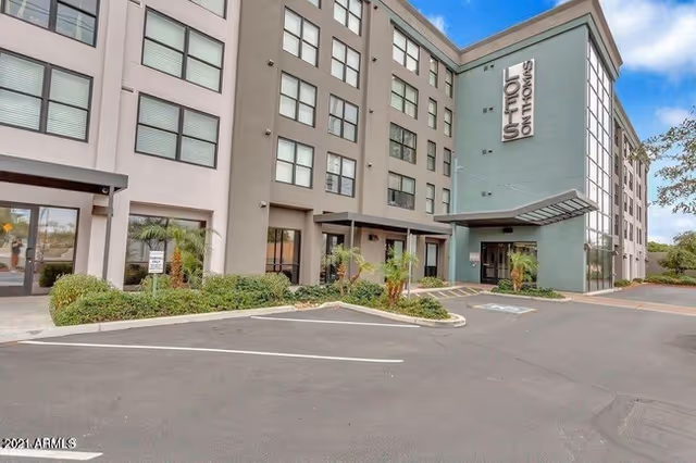 Exterior view of a multi-story senior living facility with a parking lot and entrance.