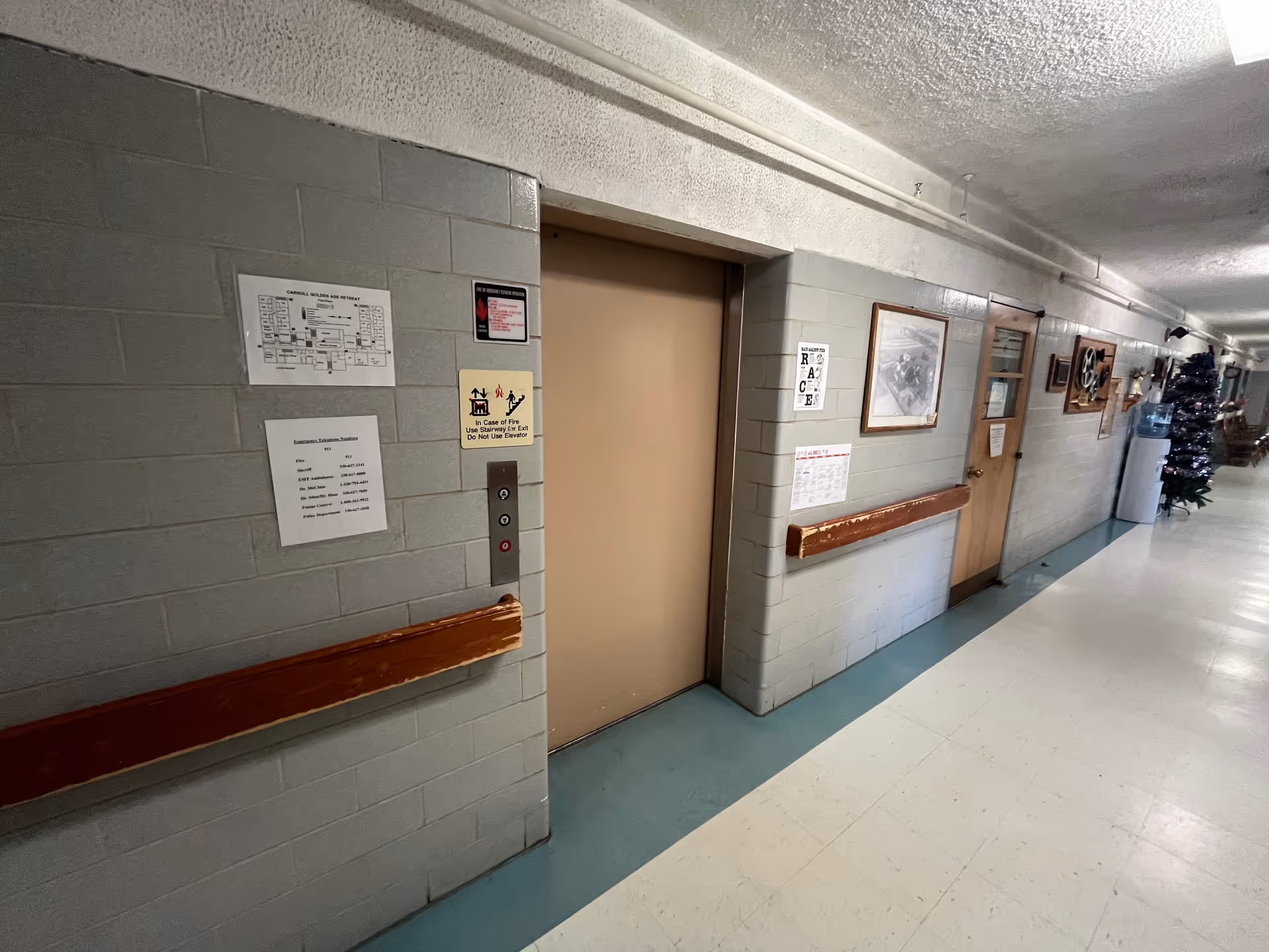 Hallway in Carroll Golden Age Retreat showing an elevator and framed pictures along the walls.