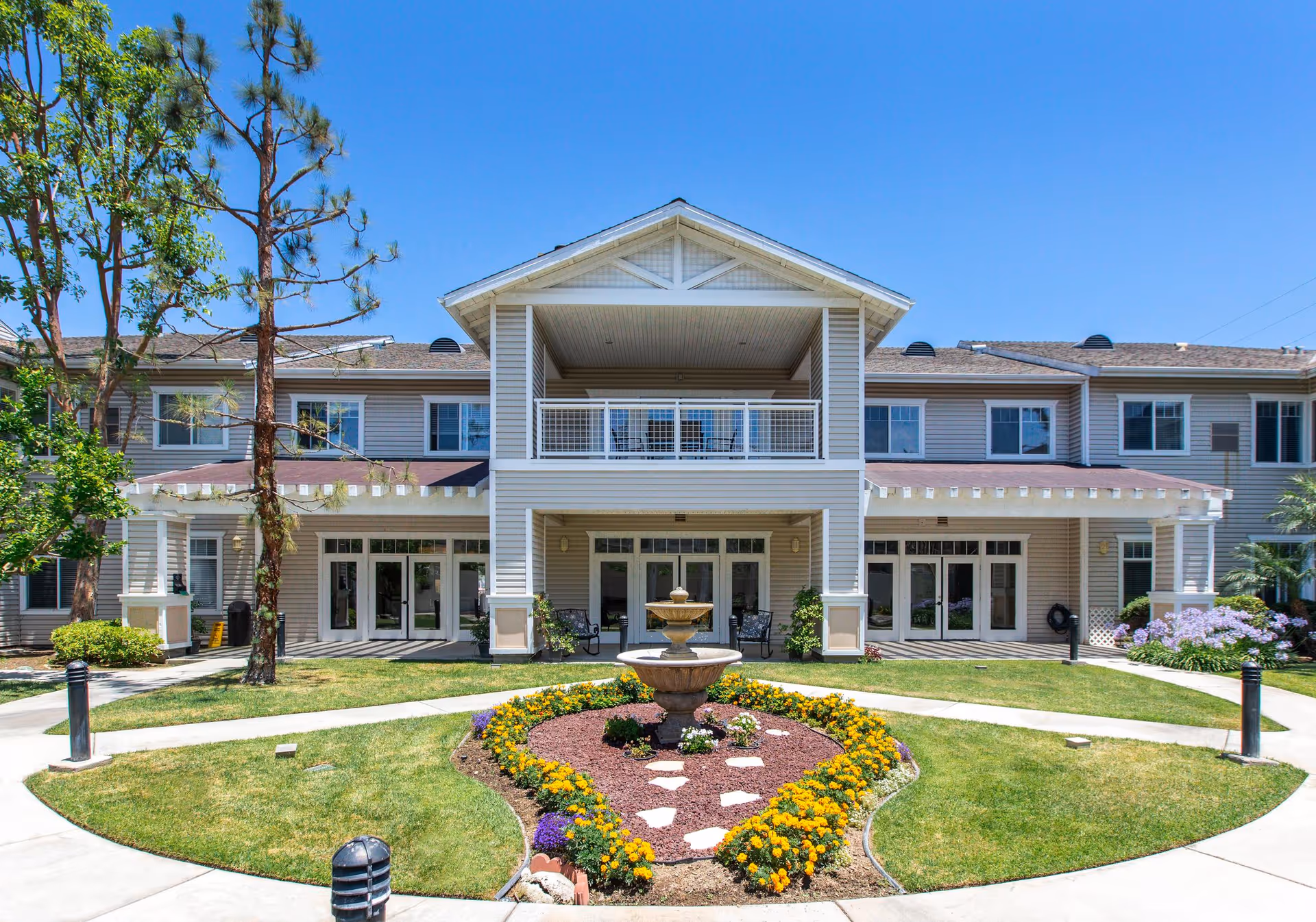Front view of a senior living building with a circular garden and fountain.