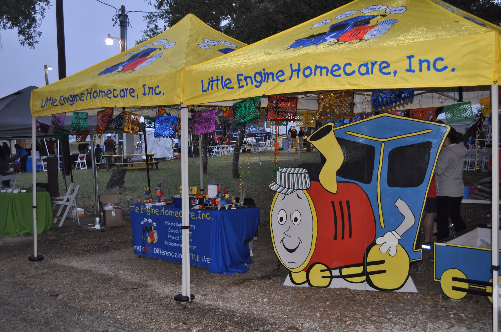 Yellow Little Engine Homecare tent at outdoor event with cartoon train prop
