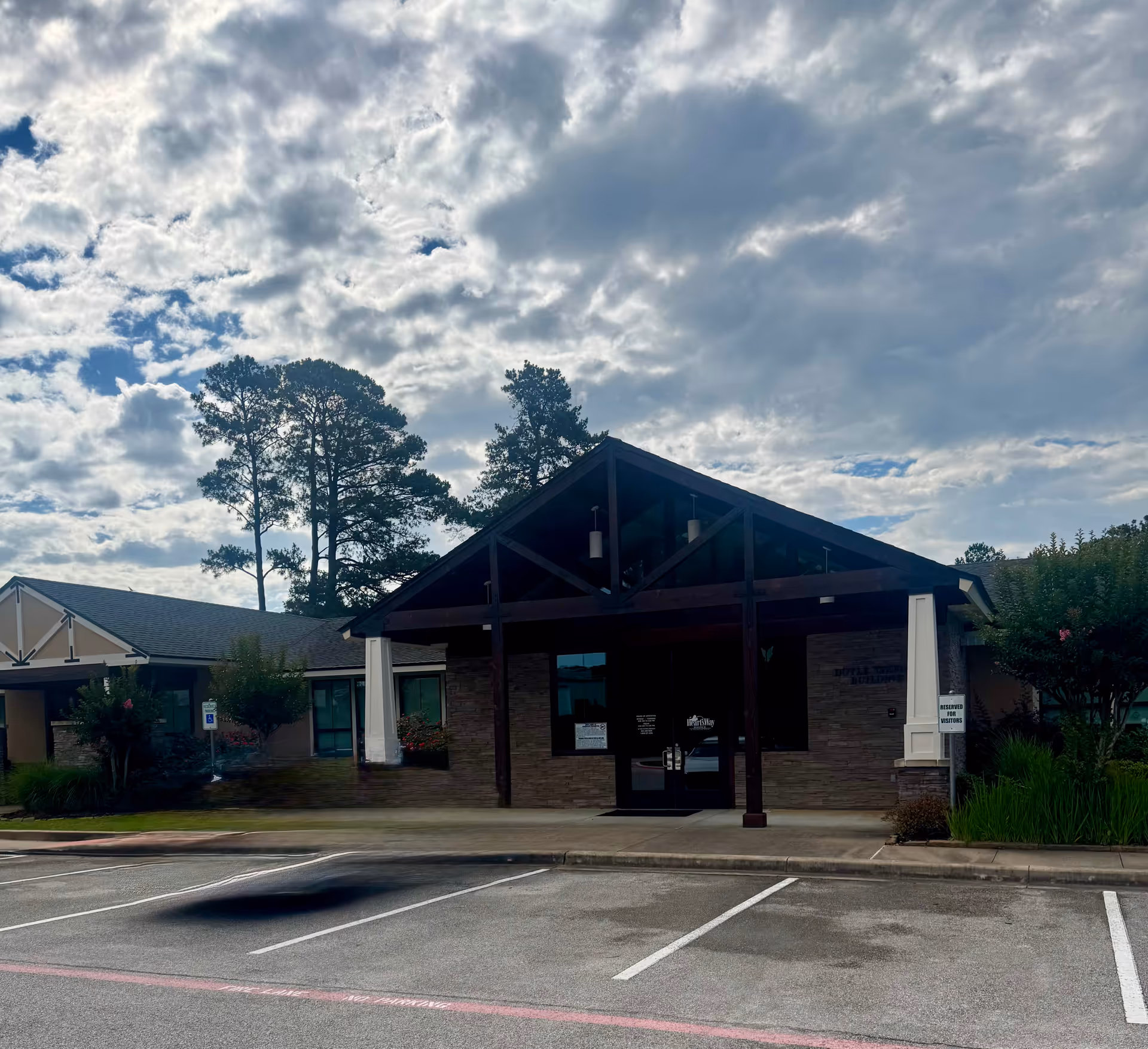 Front view of HeartsWay Hospice Longview Office building with a covered entrance and parking lot.