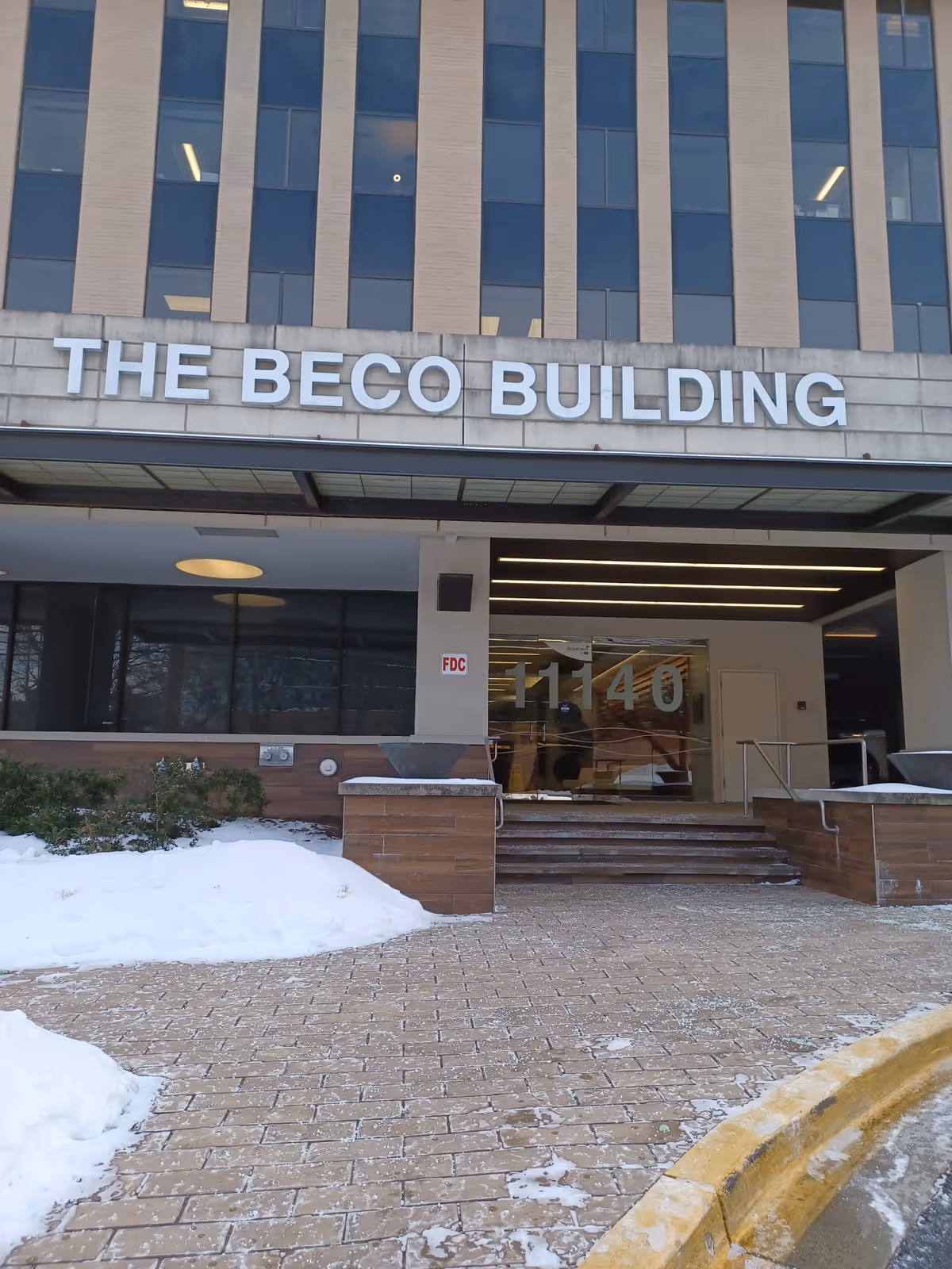 Exterior view of The BECO Building entrance with snow on the ground.