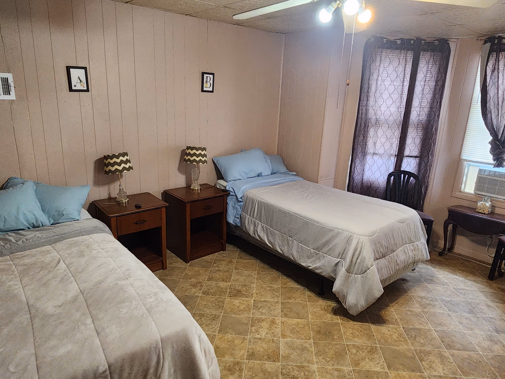 Two twin beds with blue bedding fill a small pink-paneled bedroom.