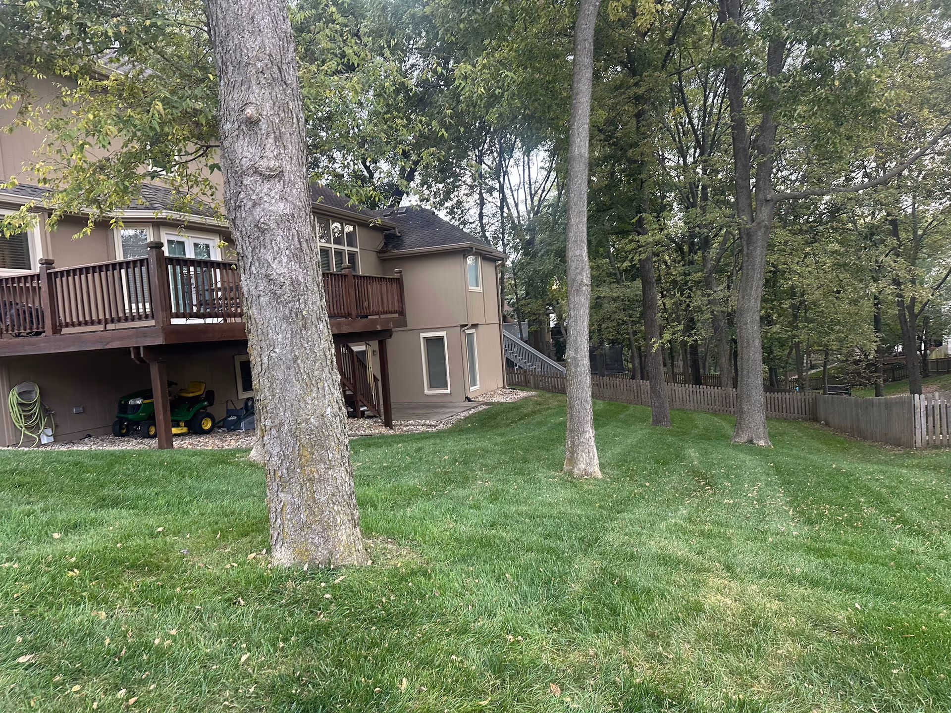 Two-story beige building with a wooden deck and expansive green lawn.