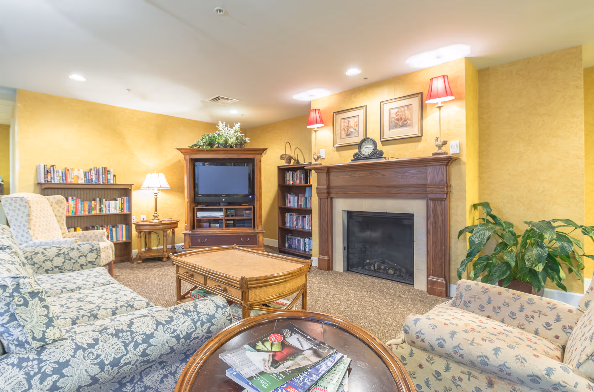 Maryfield Nursing Home living room with fireplace, bookshelves, and cushioned seating.