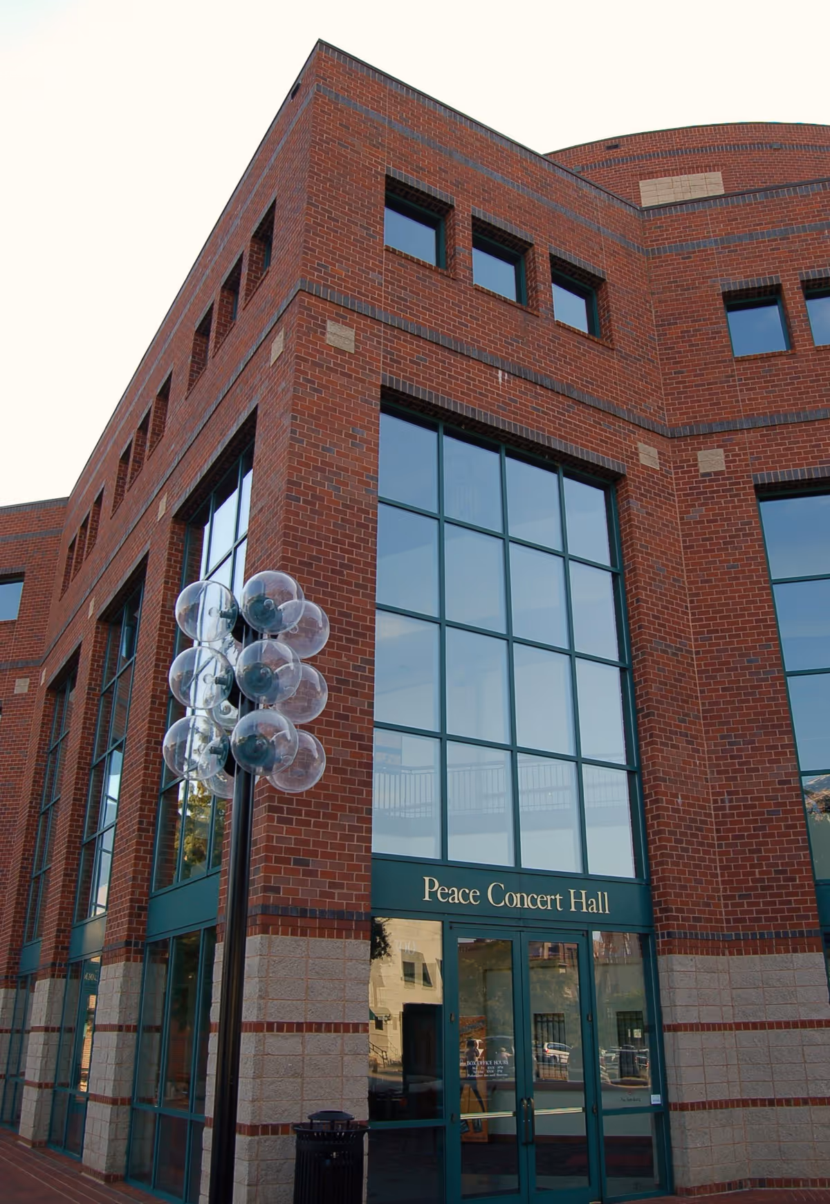 Red brick building exterior with large glass storefront entrance and streetlamp