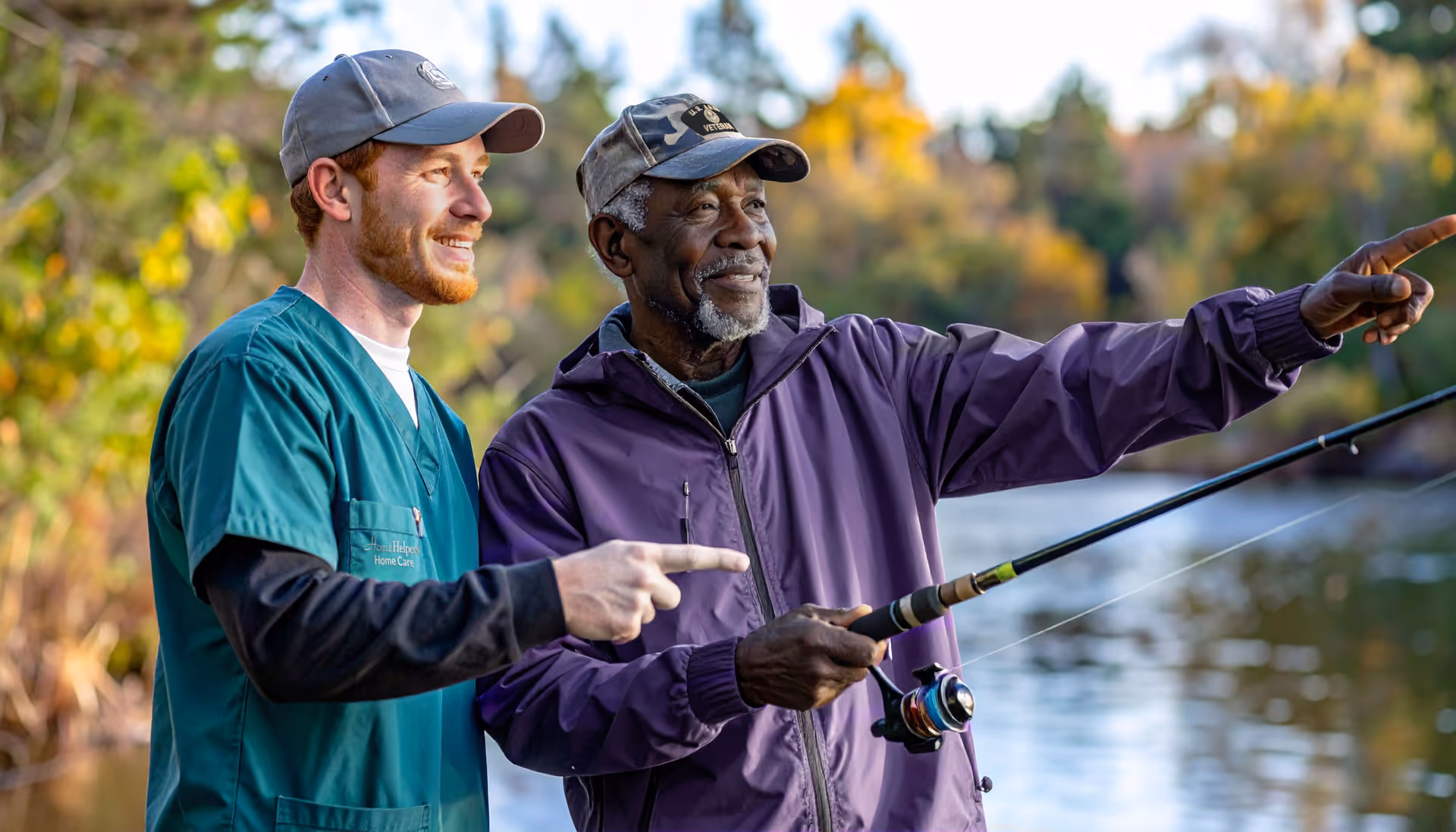 Two people fish by a lake, one assisting the other outdoors.