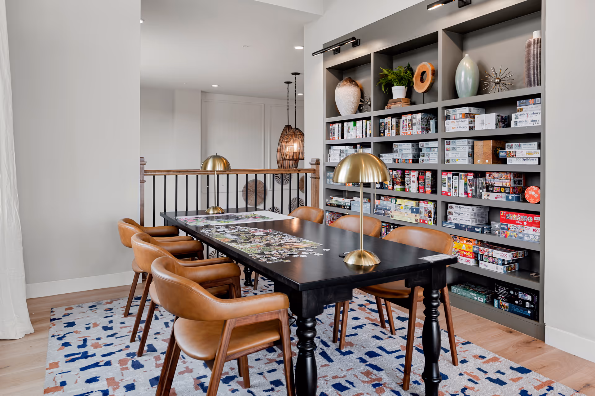 A modern game room with a black table, brown chairs, and a wall of board games.