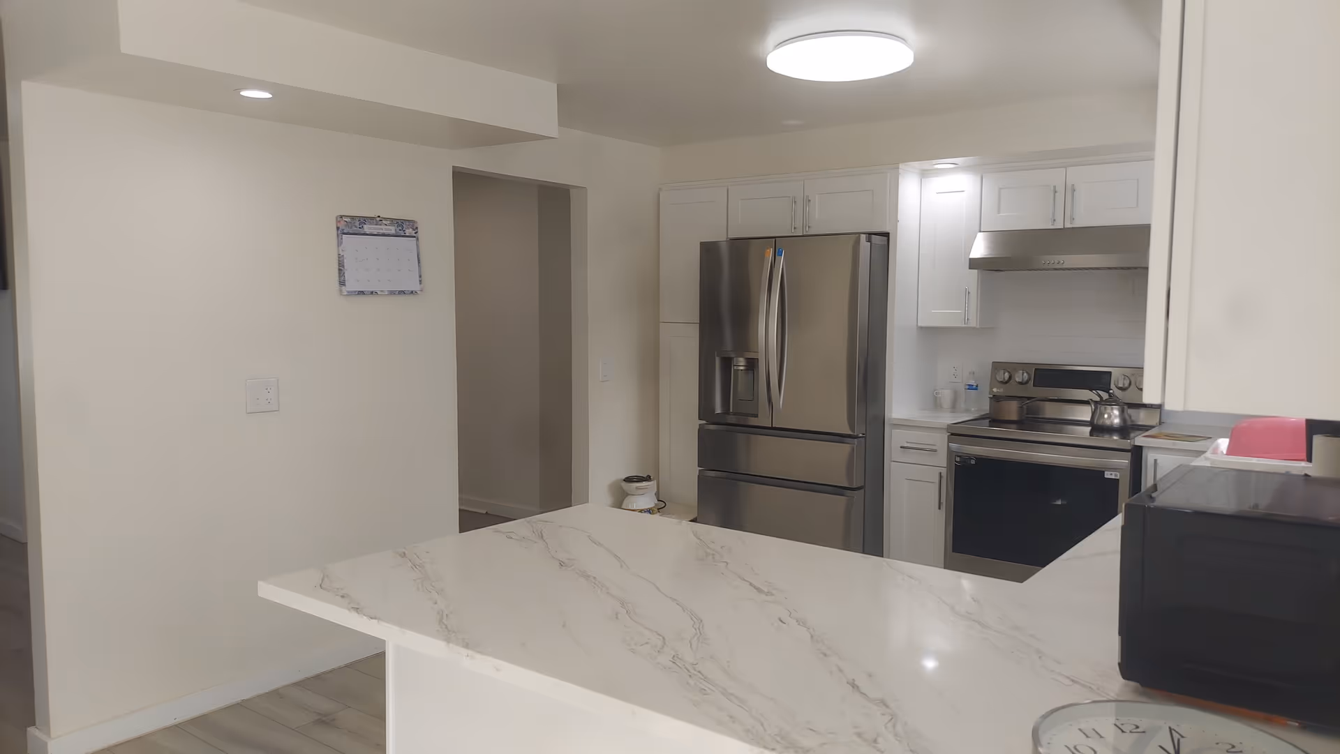 Bright modern kitchen with white cabinets, stainless appliances, and a marble island.