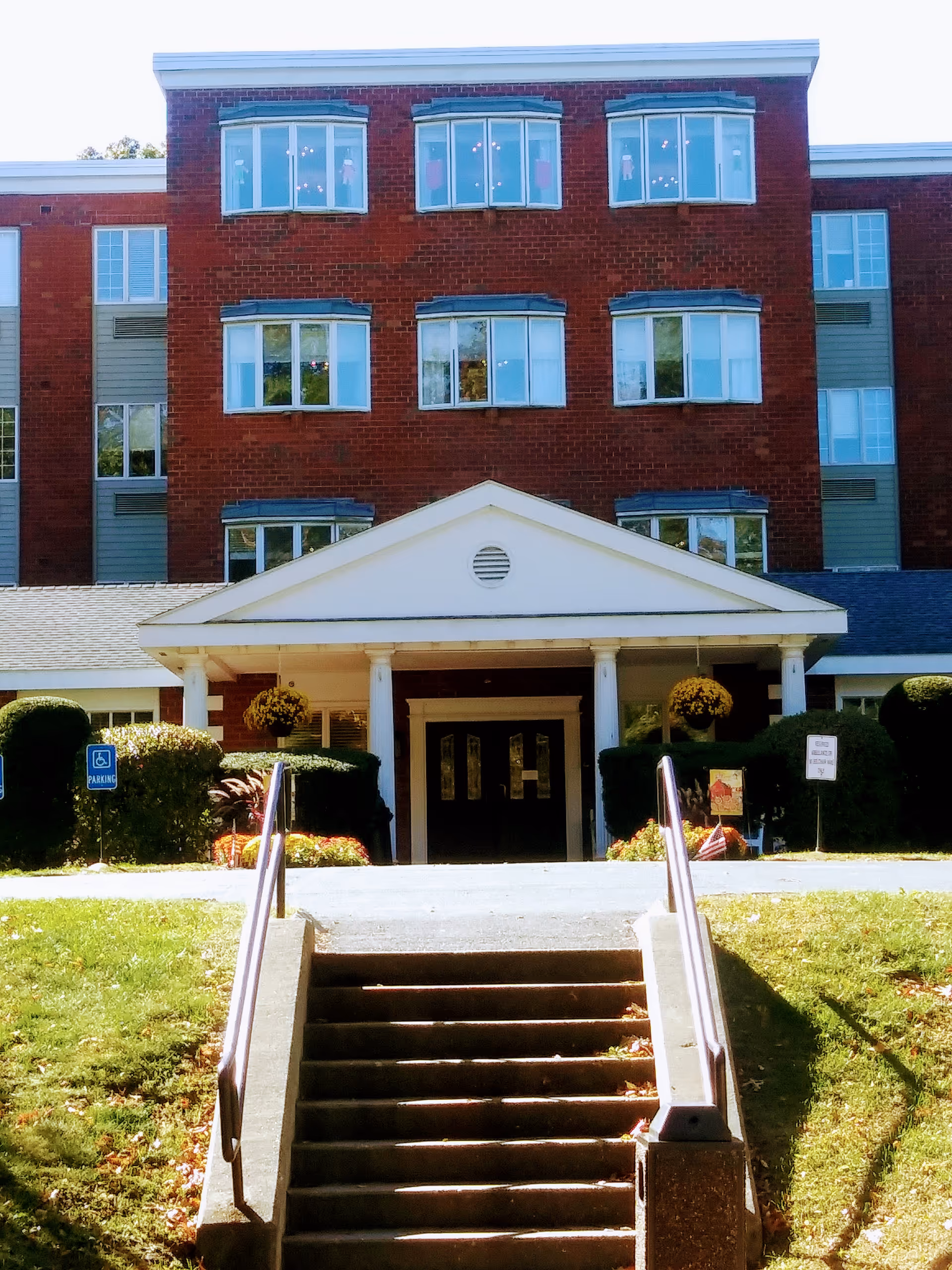 Brick four-story building with a white columned entrance and stairs.