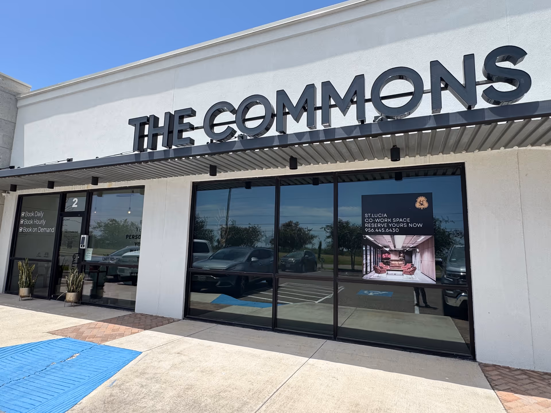 Exterior storefront with THE COMMONS sign, glass windows, and potted entrance plants.