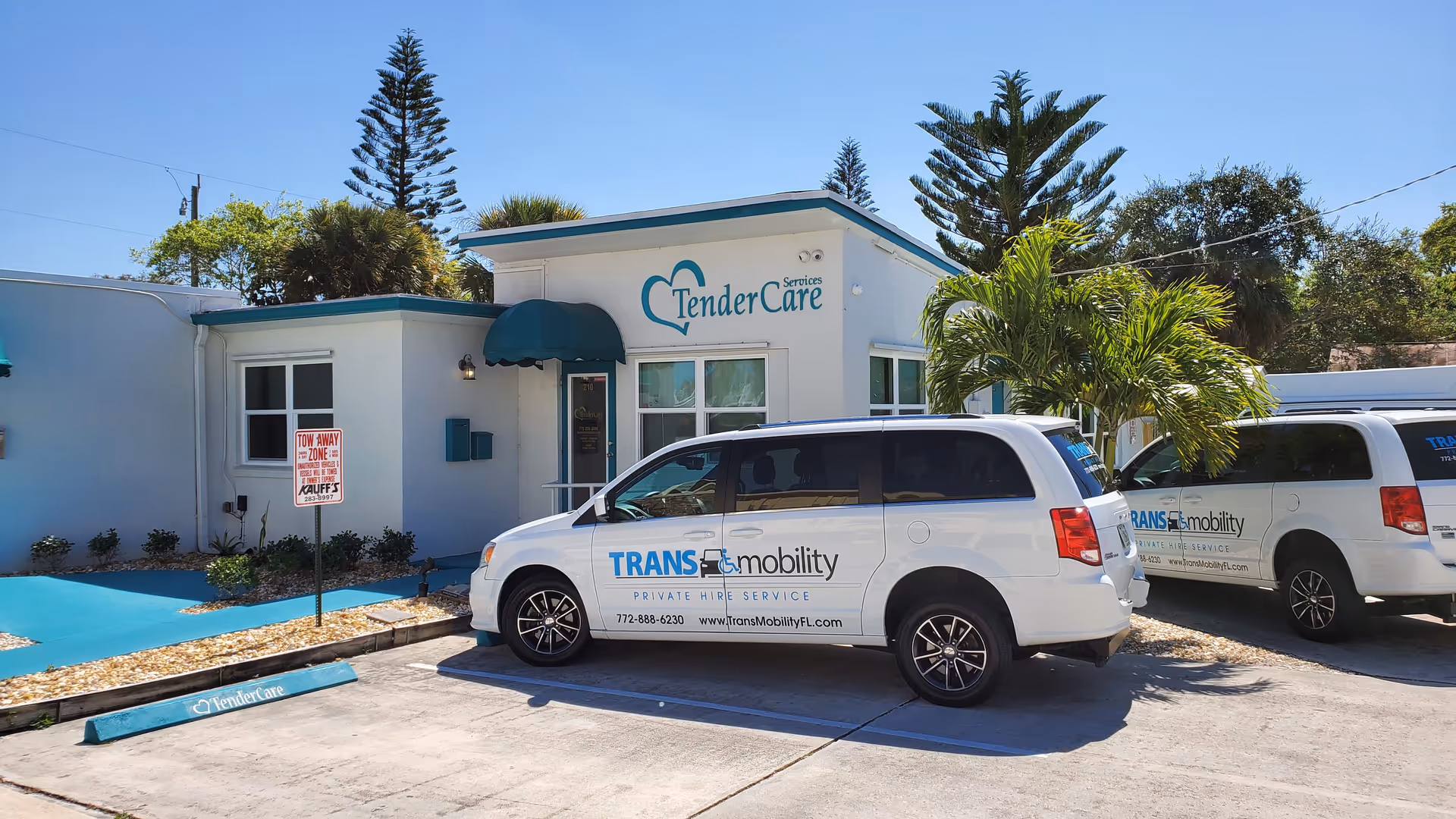 Exterior view of TenderCare Services building with parked TransMobility vans in a sunny lot