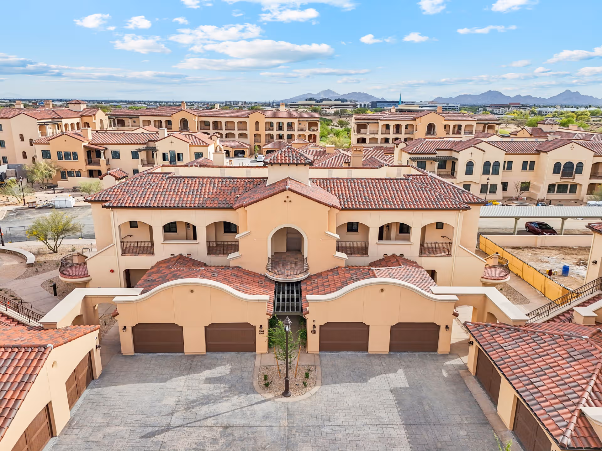 Aerial view of a senior living campus with tan stucco and red-tiled roofs.