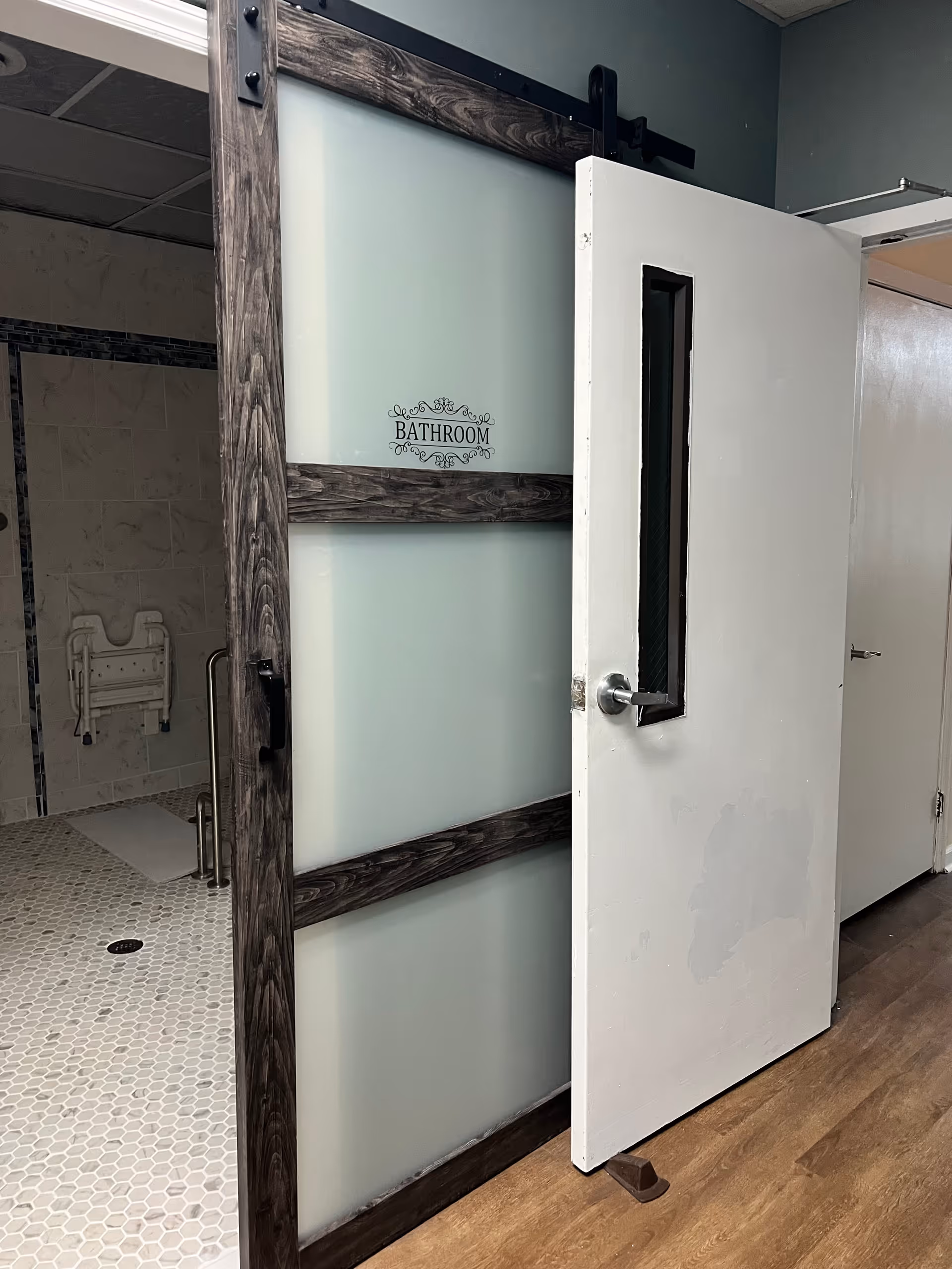 Partial view of a bathroom behind a sliding frosted door with a shower area.