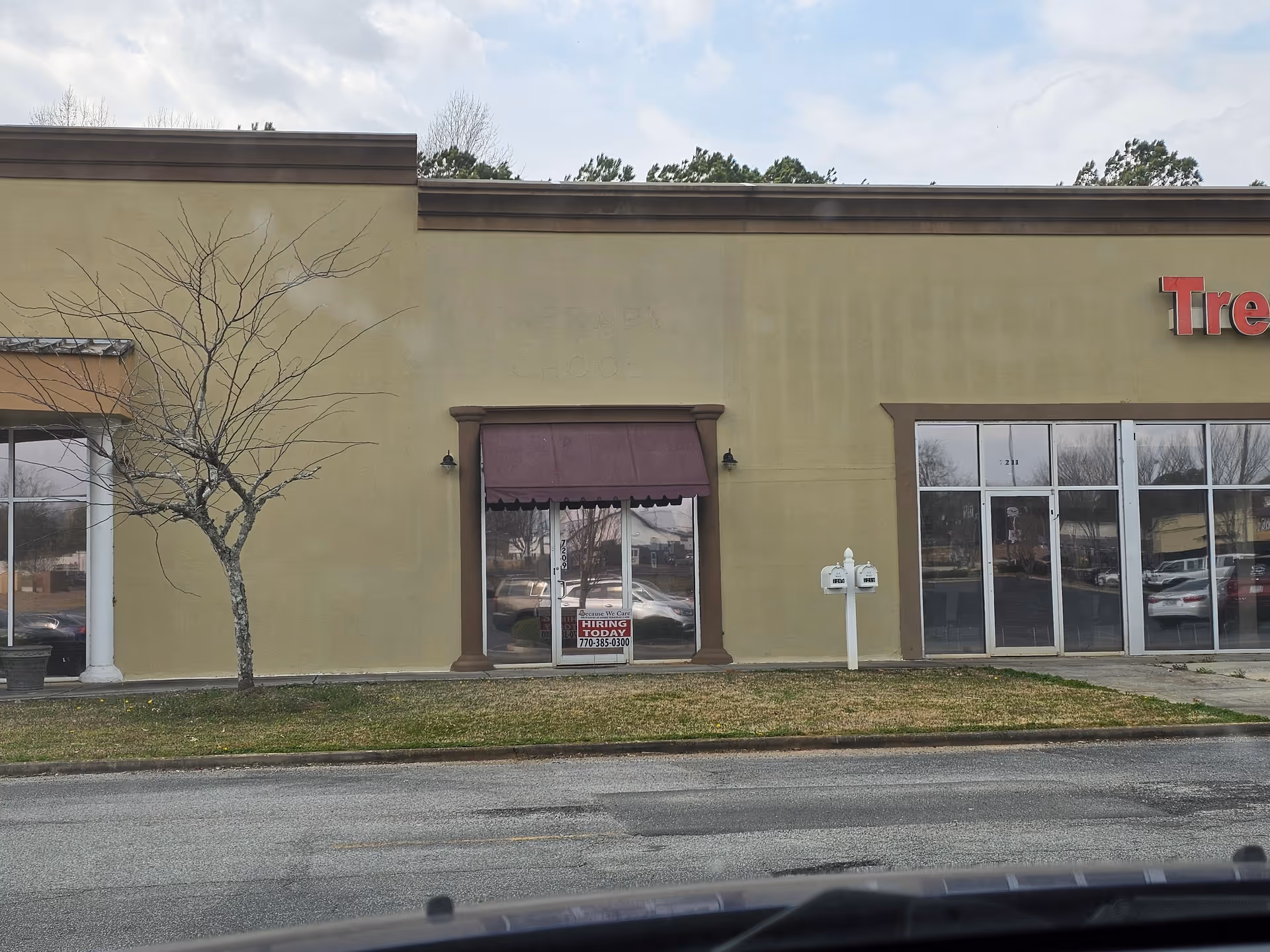 Front exterior of a beige senior living facility with a storefront entrance