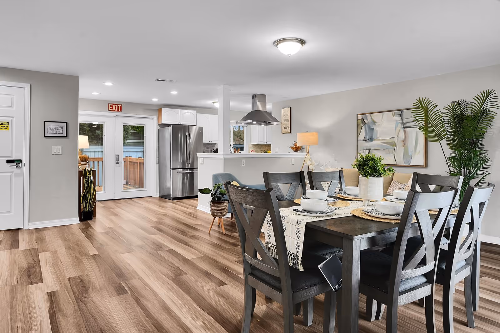 A spacious dining area with a dark wood table set for meals and a bright kitchen.