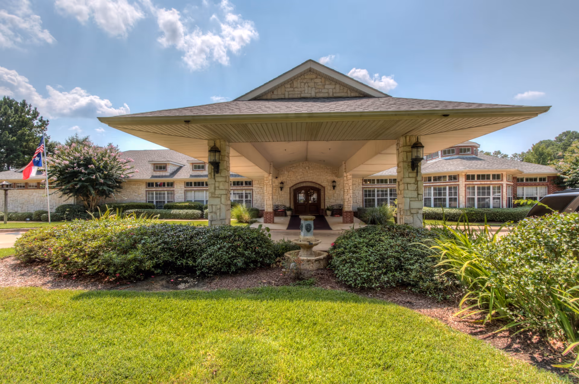Front entrance of Arabella of Kilgore Senior Living with stone columns and landscaping.