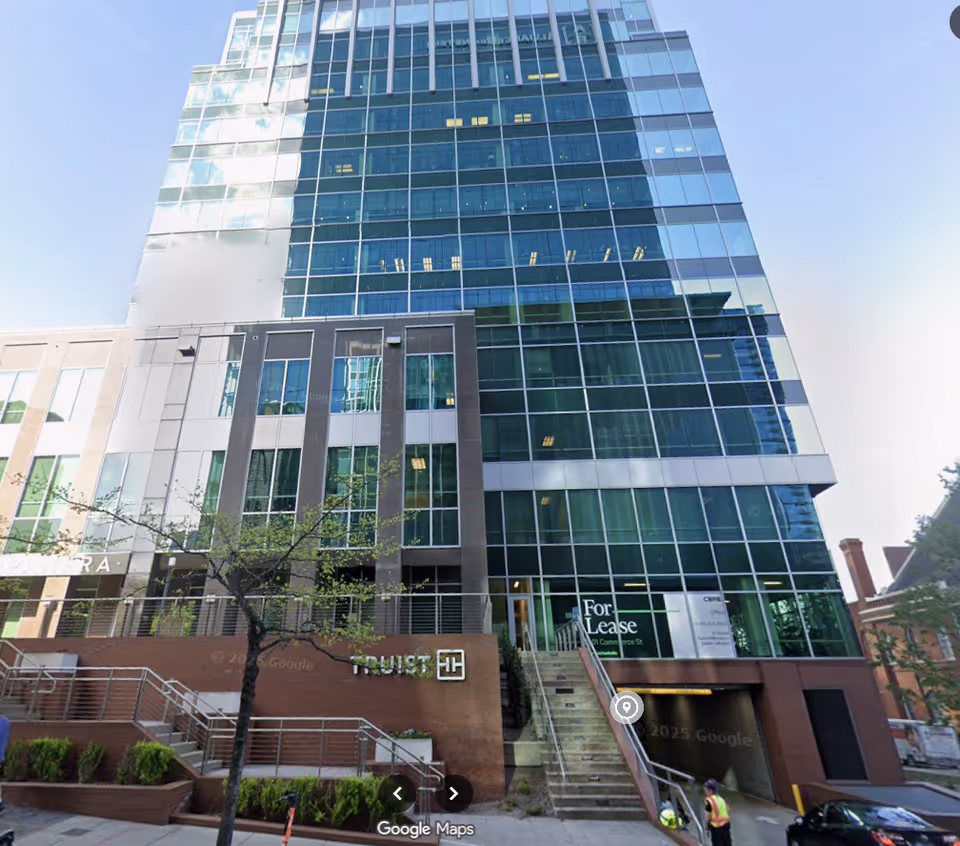 Tall glass-front building with modern architecture and street-level stairs.