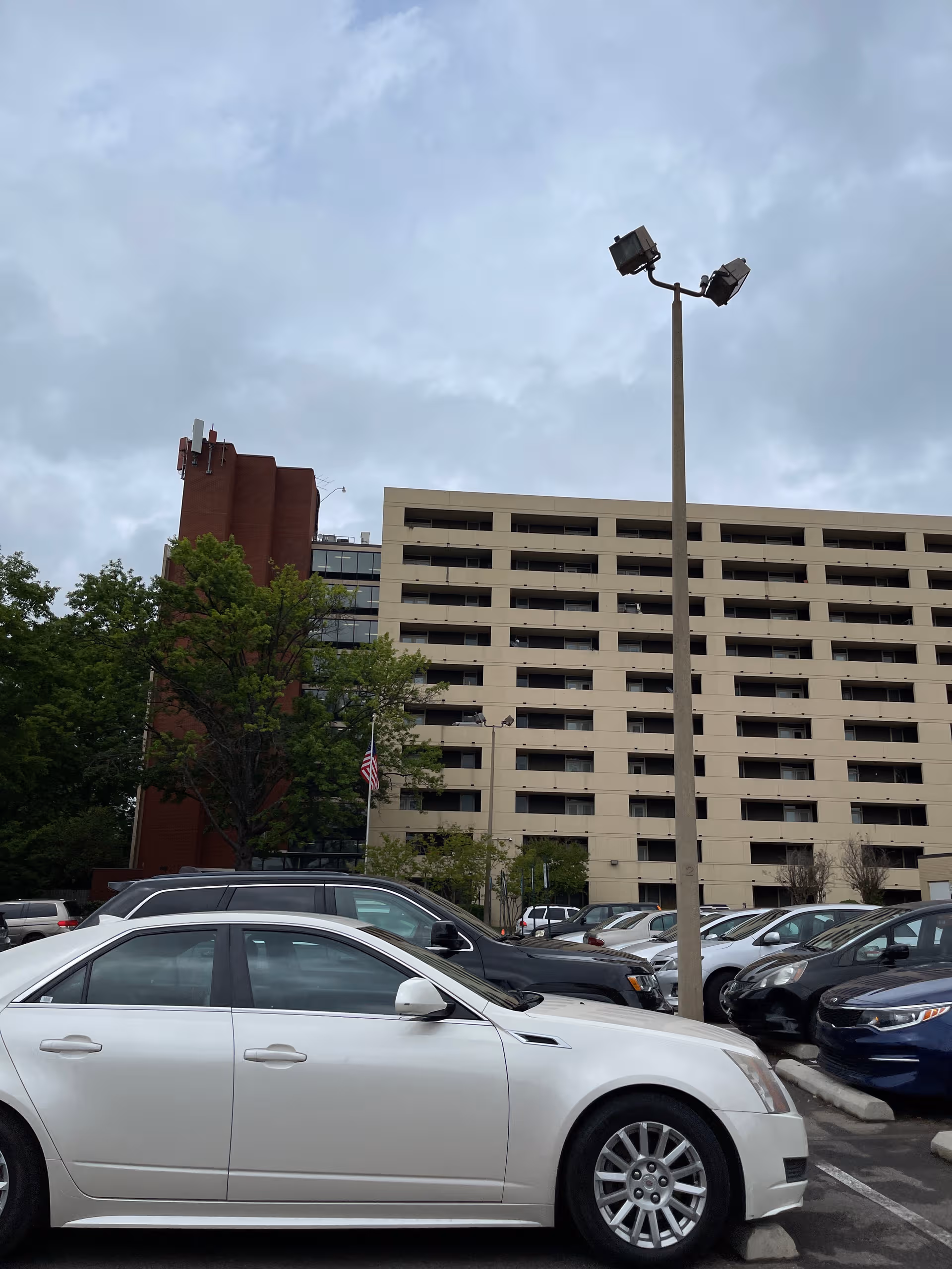 Exterior view of St. Peter Manor Senior Living with parked cars and a tall light pole.