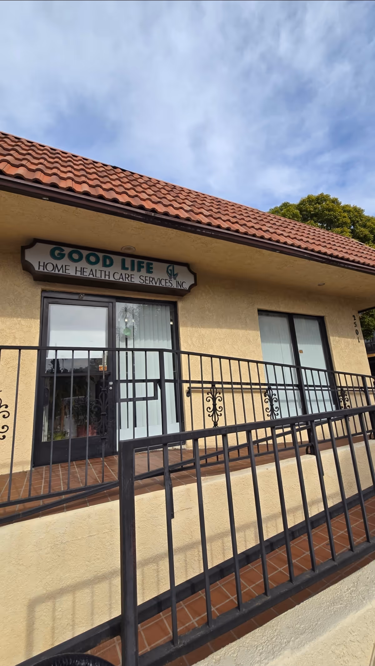 Exterior view of Good Life Home Health Care Services building with sign and railing.