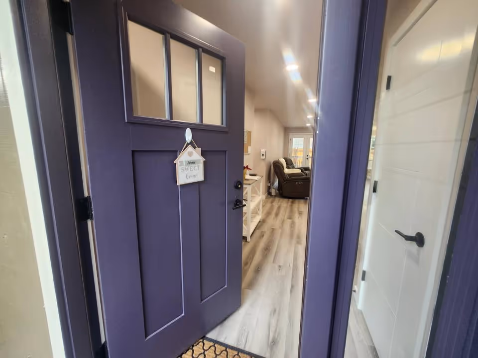 A view from the entrance of a senior living facility, featuring a purple front door and a glimpse of the living area inside.