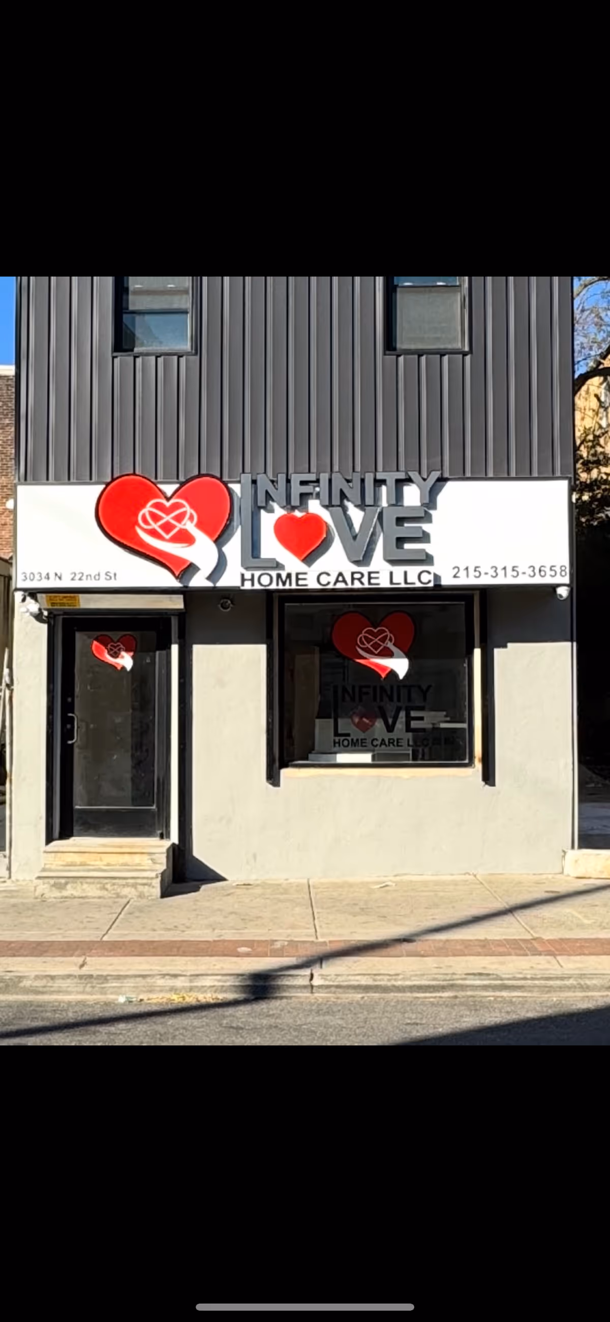 Storefront of Infinity Love Home Care LLC with heart logo signage on a gray building.