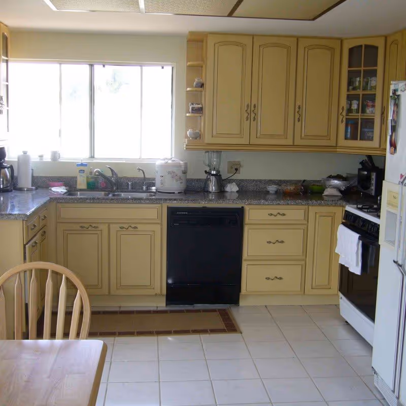 Bright kitchen with beige cabinets, granite countertops, sink, and appliances beside a large window.