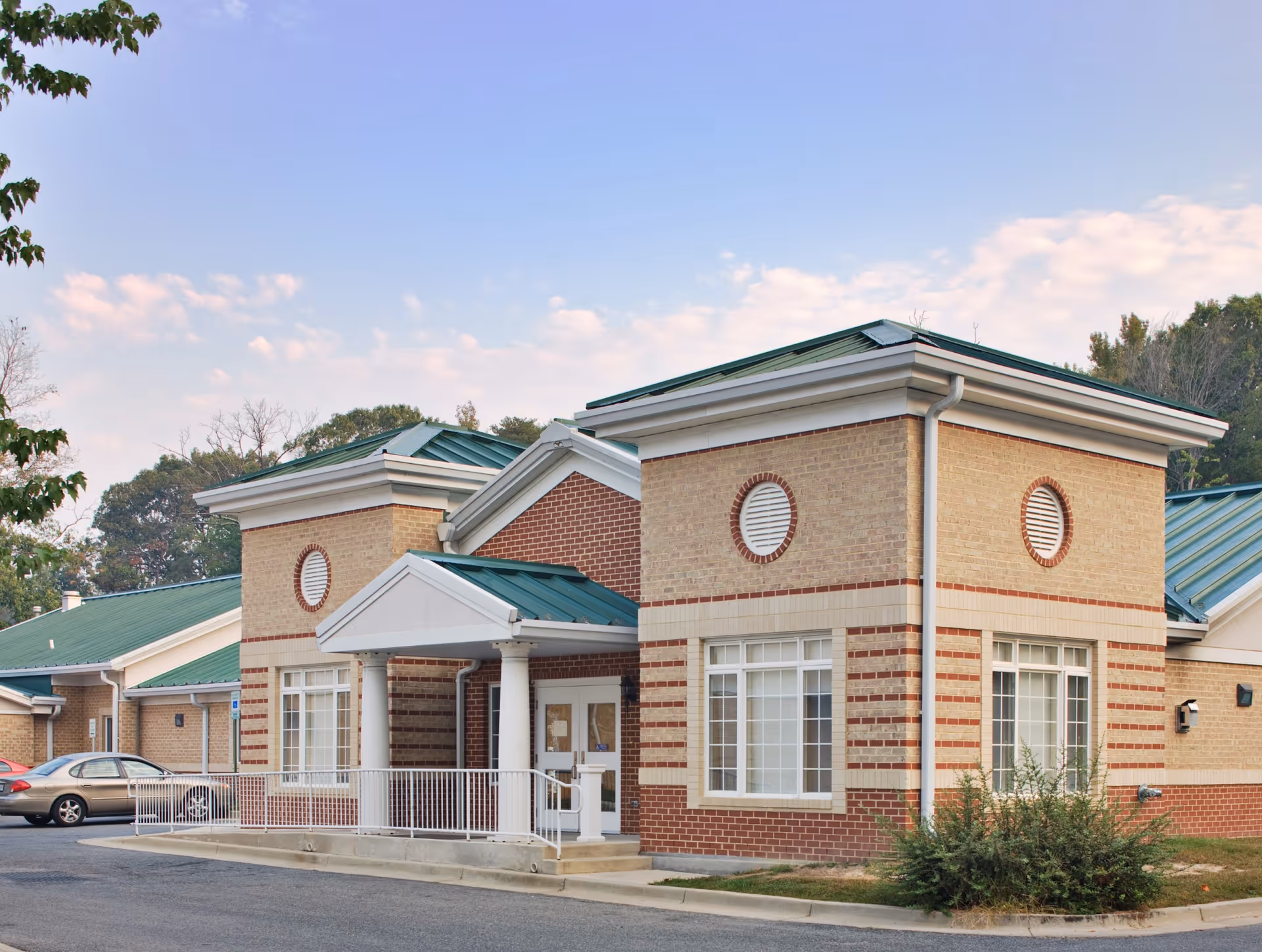 Exterior view of a brick senior living center with green roof and entrance porch.