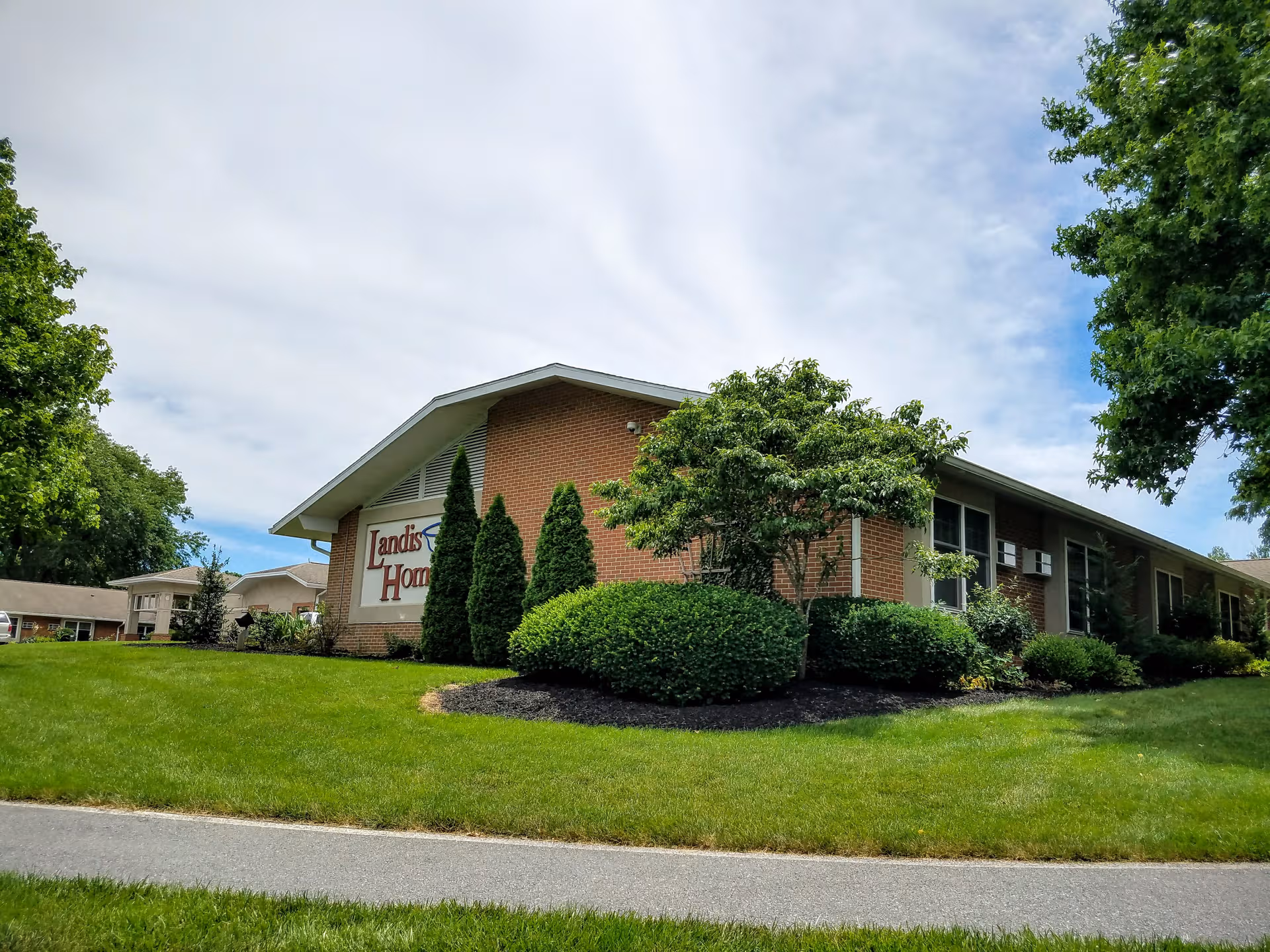 Exterior view of Landis Homes facility with brick building, sign, and landscaped grounds.