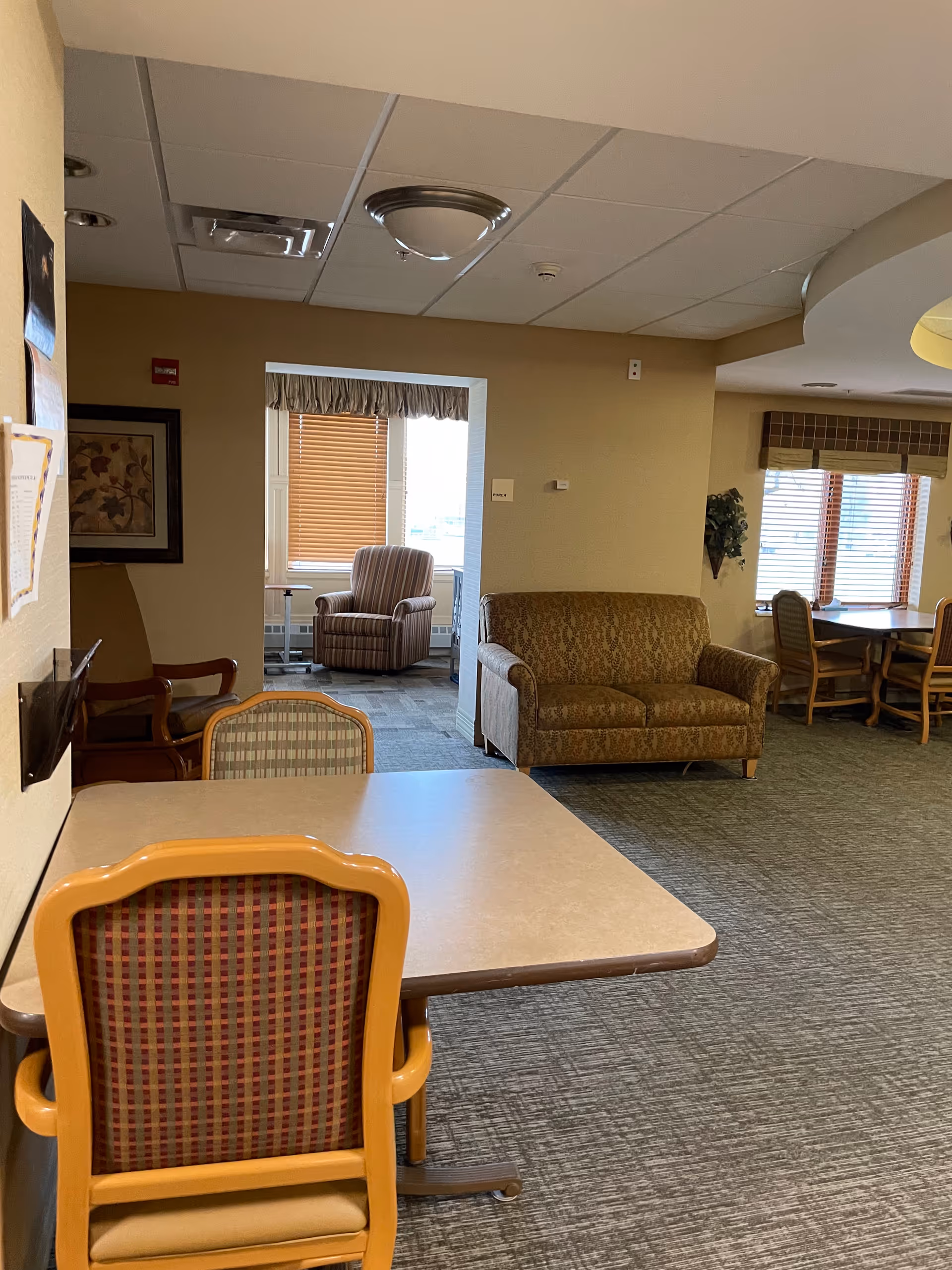 Interior lounge area with a table, chairs, and sofas in a senior living center.