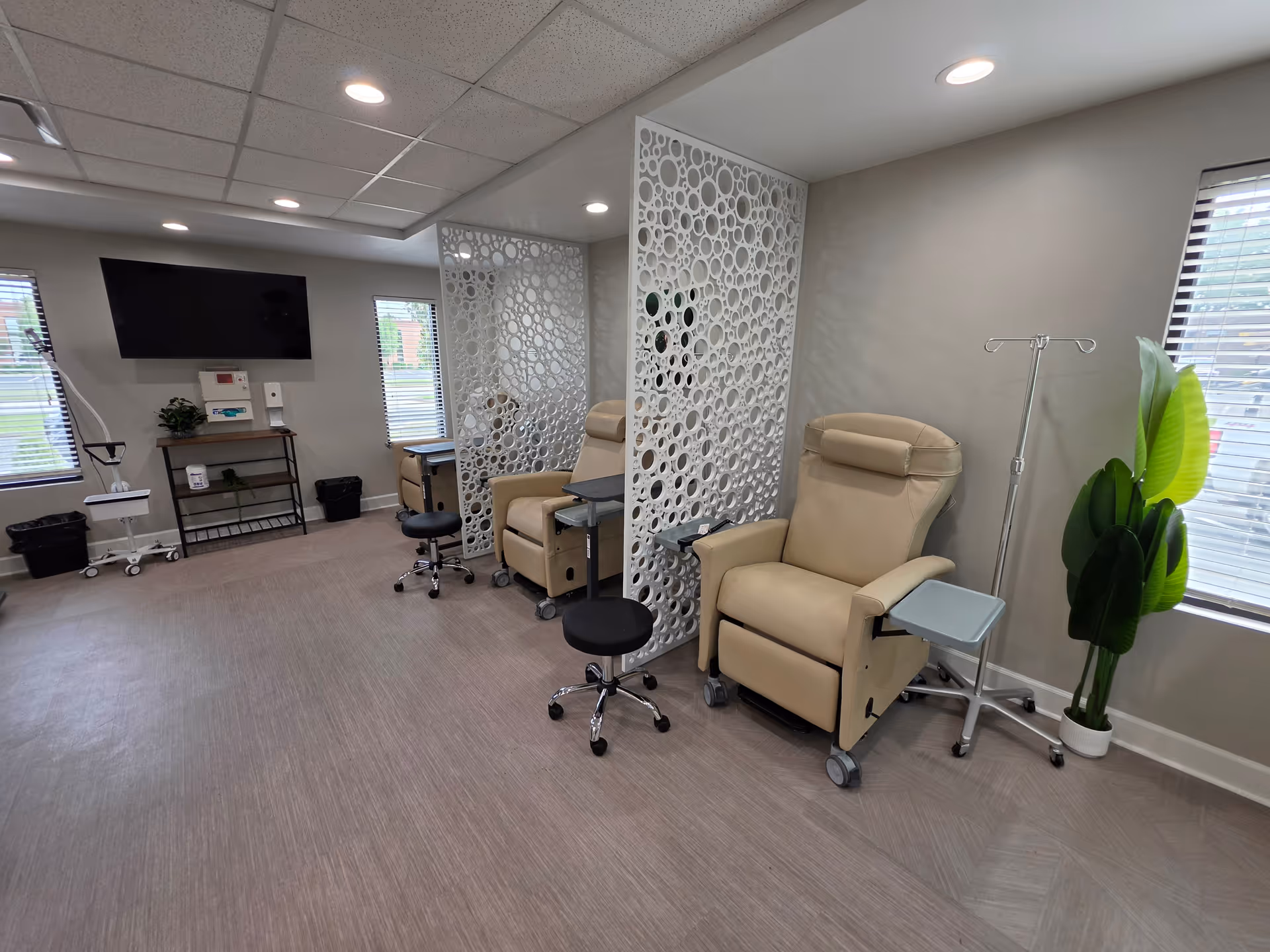 Infusion chairs and privacy screens in a modern infusion treatment room with medical equipment.