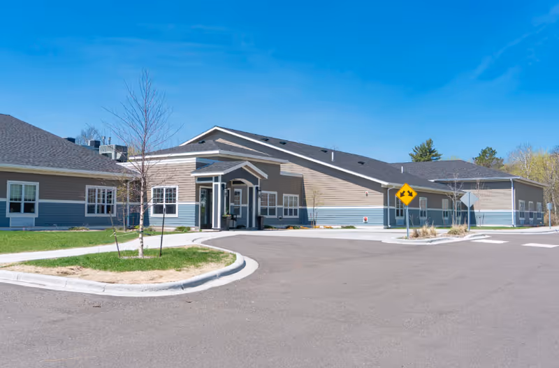 Exterior of a single-story senior living facility with entrance canopy and parking.
