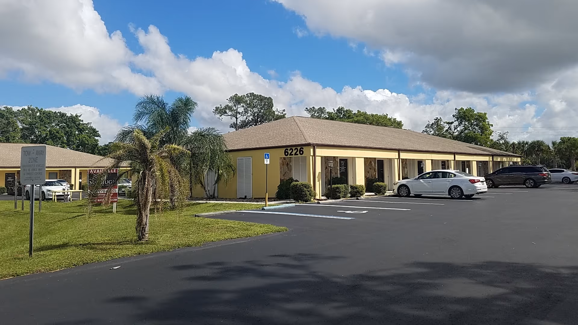 Single-story beige senior care facility with a parking lot and palm trees in front