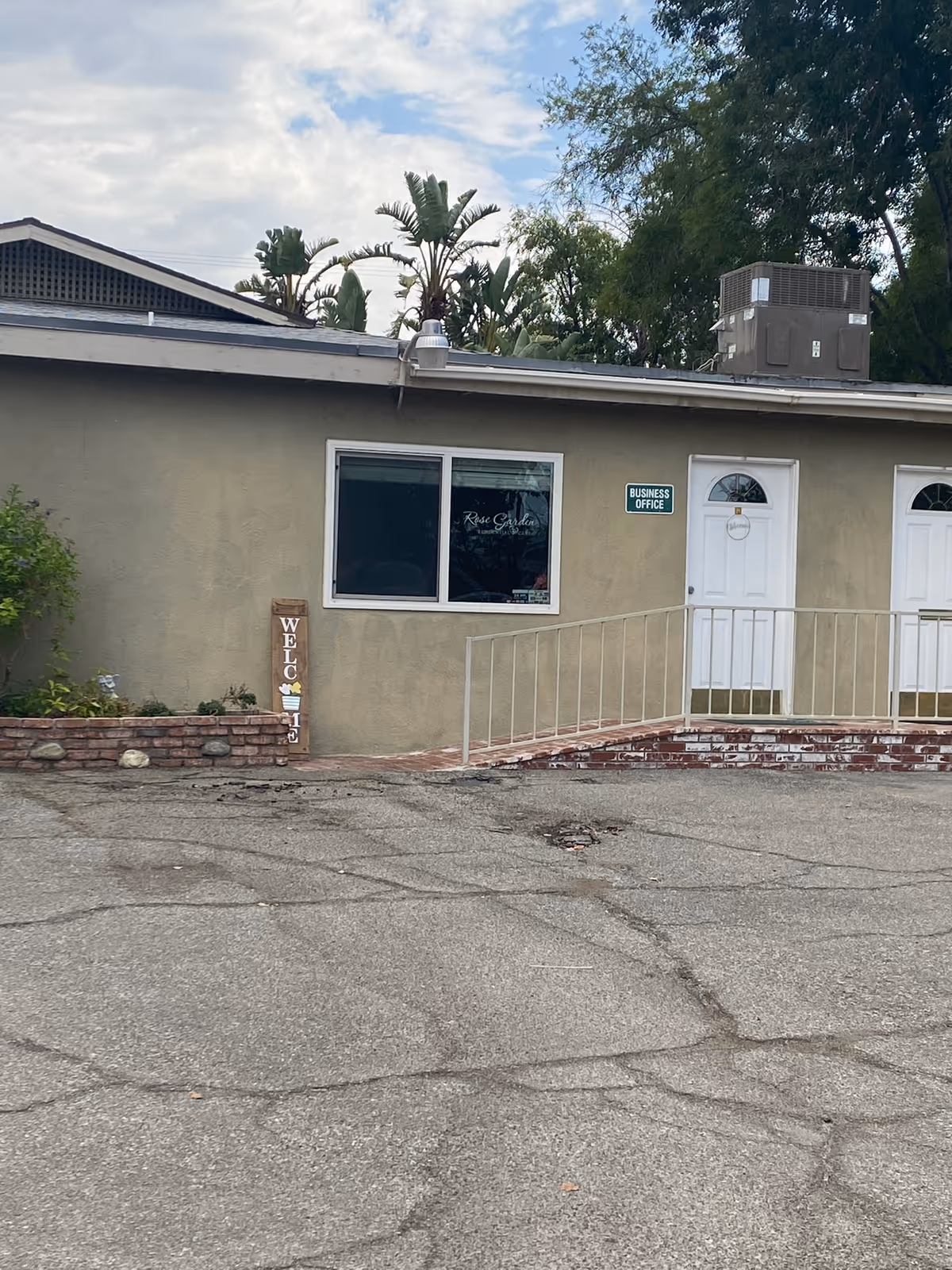 Exterior view of Rose Garden Residential Care with a ramp, front doors, and sign.