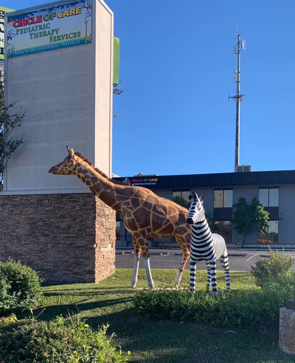 Two large animal statues, a giraffe and a zebra, stand outside Circle of Care corporate office.