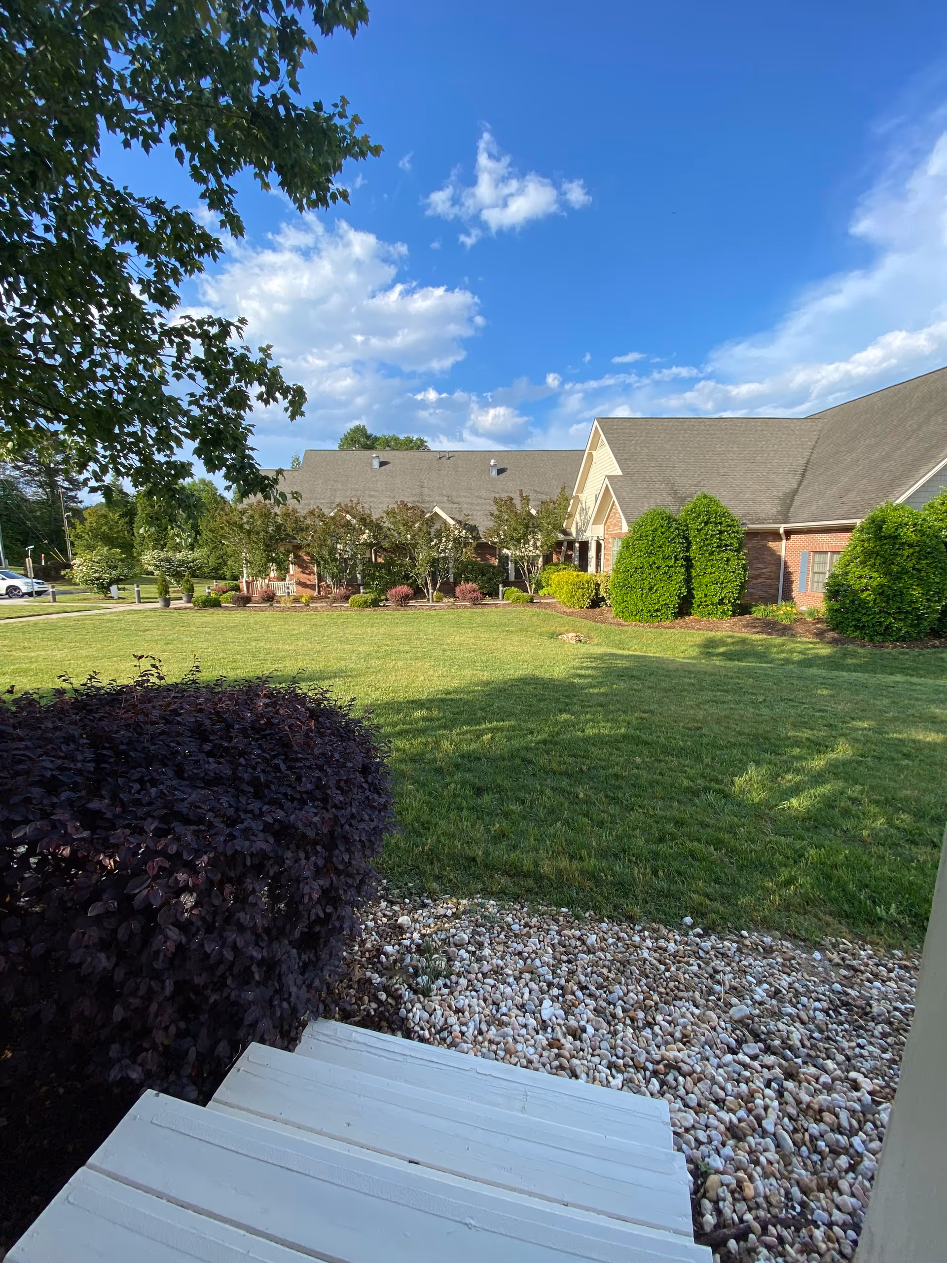Exterior view of AMOREM senior living facility with manicured lawn and shrubs.