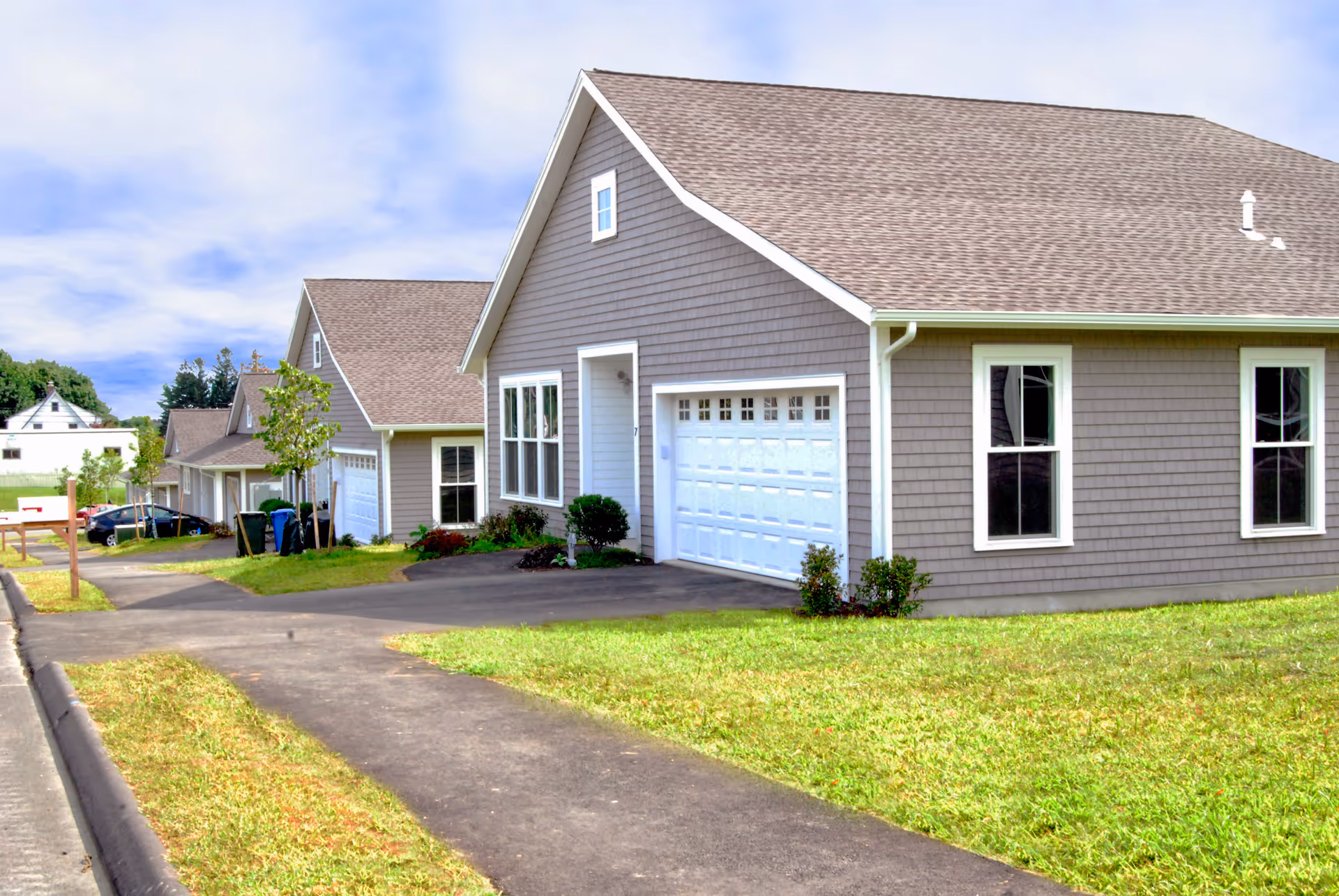 Exterior view of Fairview senior living cottages with garages and manicured lawns.