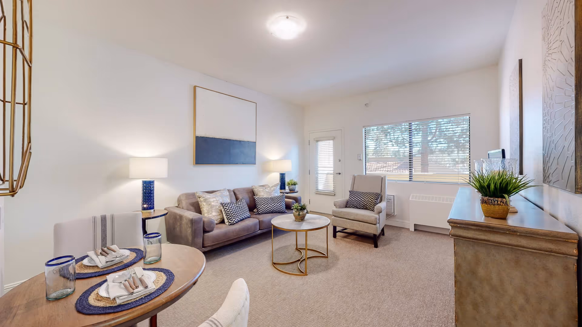 Bright living room with sofa, armchairs, and a round coffee table in neutral tones.